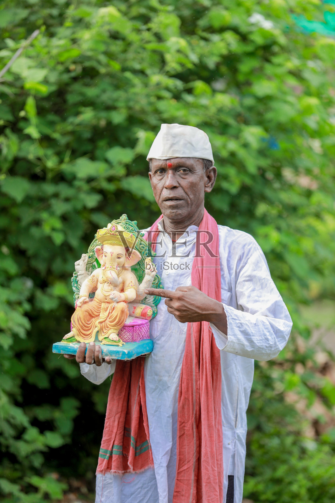 印度老人手里拿着甘尼萨神神像,快乐的可怜老人照片摄影图片