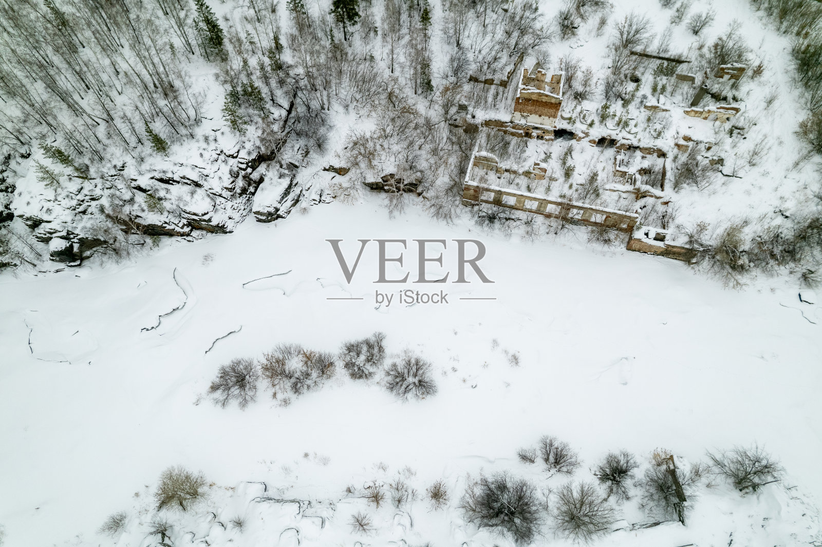 鸟瞰图,一条冰雪覆盖的河流和一座废弃的老房子照片摄影图片