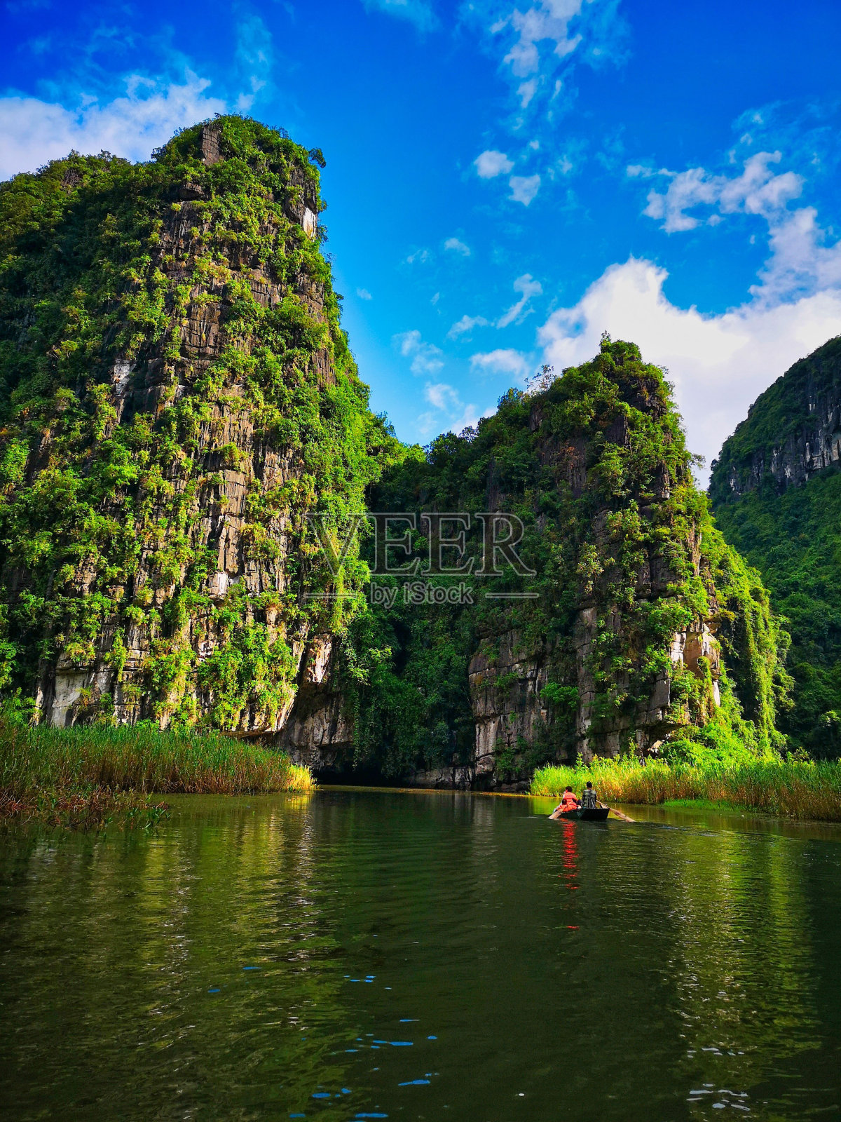 在越南宁平,游客们乘船沿着被群山环绕的河流而行照片摄影图片