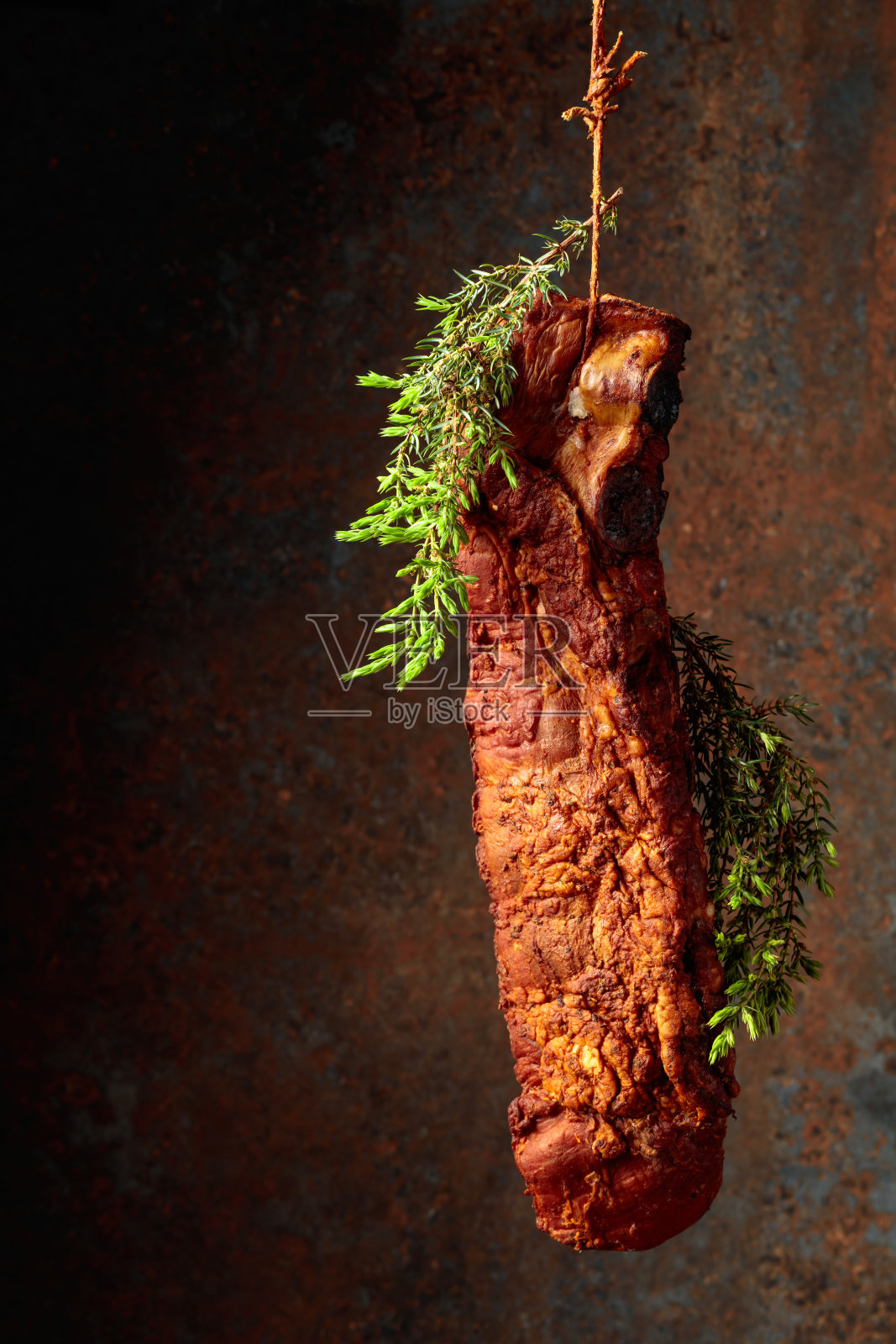 在生锈的背景上,熏猪排配杜松枝。照片摄影图片