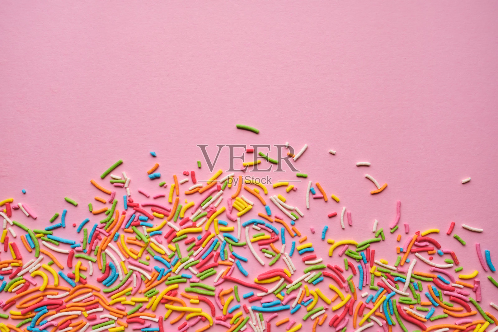 五彩缤纷的糖果点缀在粉红色的上面。照片摄影图片