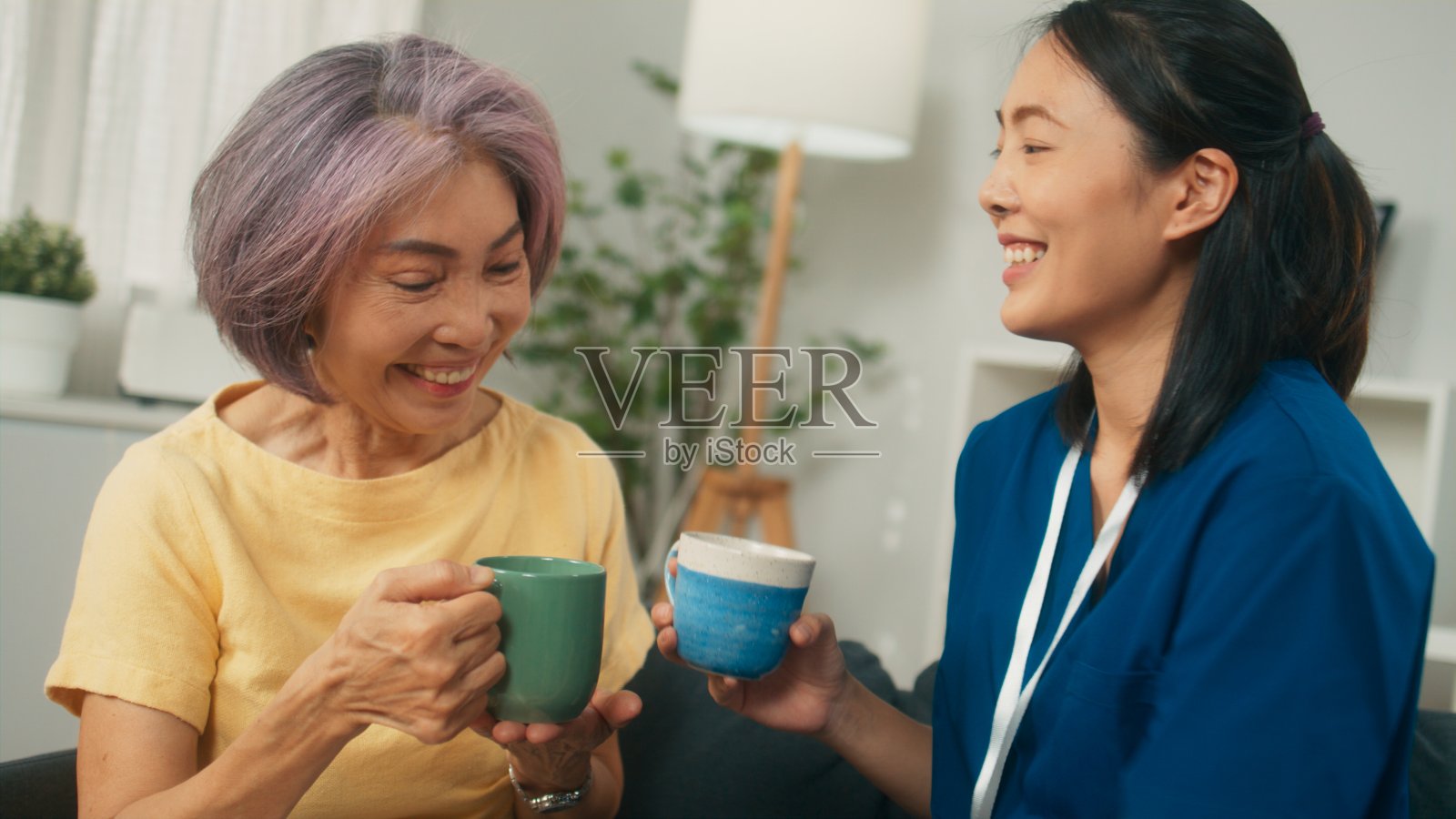 家访时,保健专家在客厅与快乐的女病人聊天,一起喝茶照片摄影图片