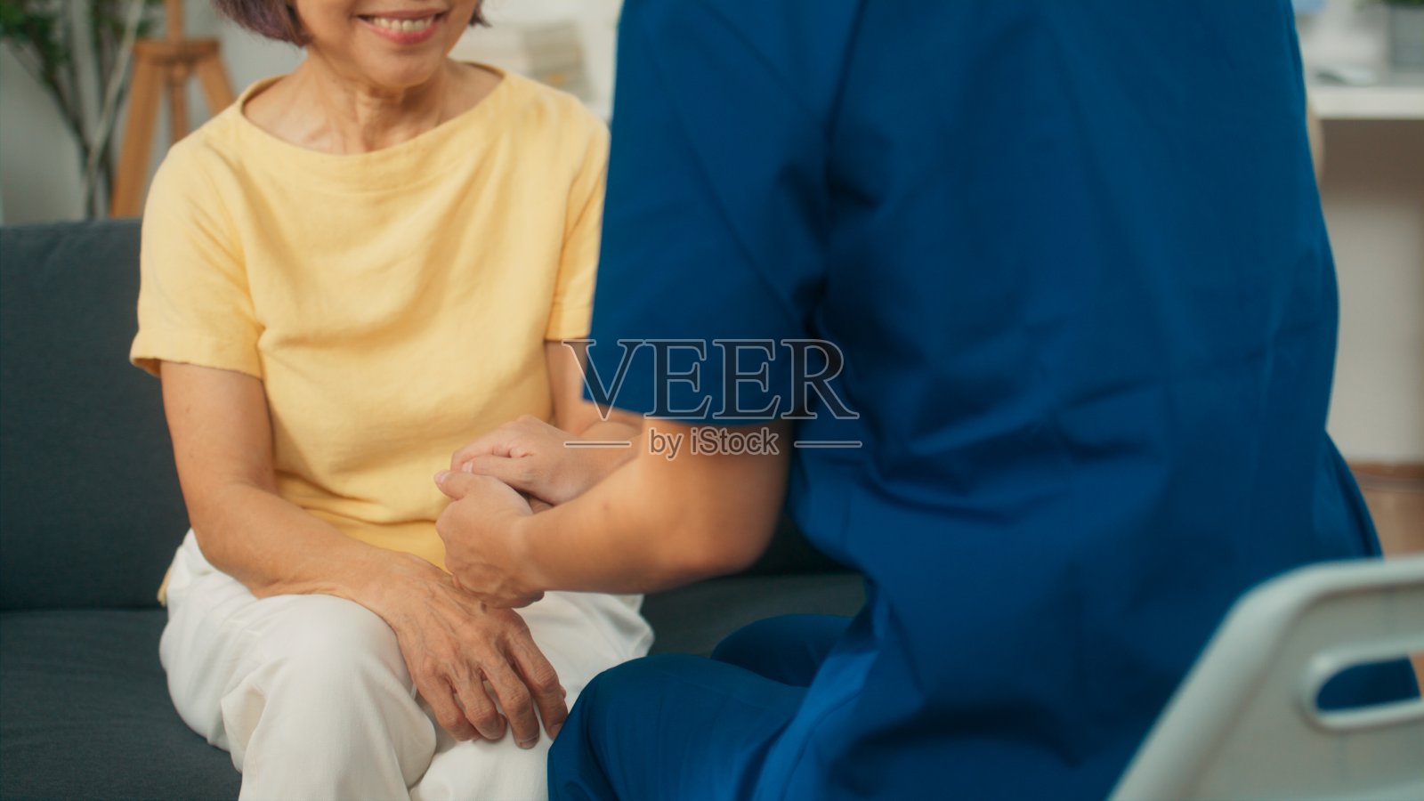 医生触摸退休老人的手给予同情和鼓励,年轻护理护士在家访中提供照顾和支持照片摄影图片