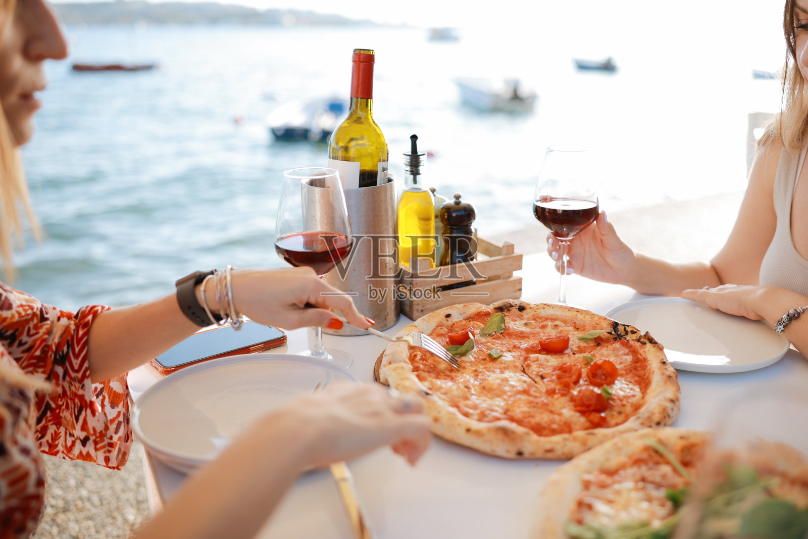 两位女性朋友在夏日街咖啡馆外面的露台上笑着喝酒的特写照片摄影图片