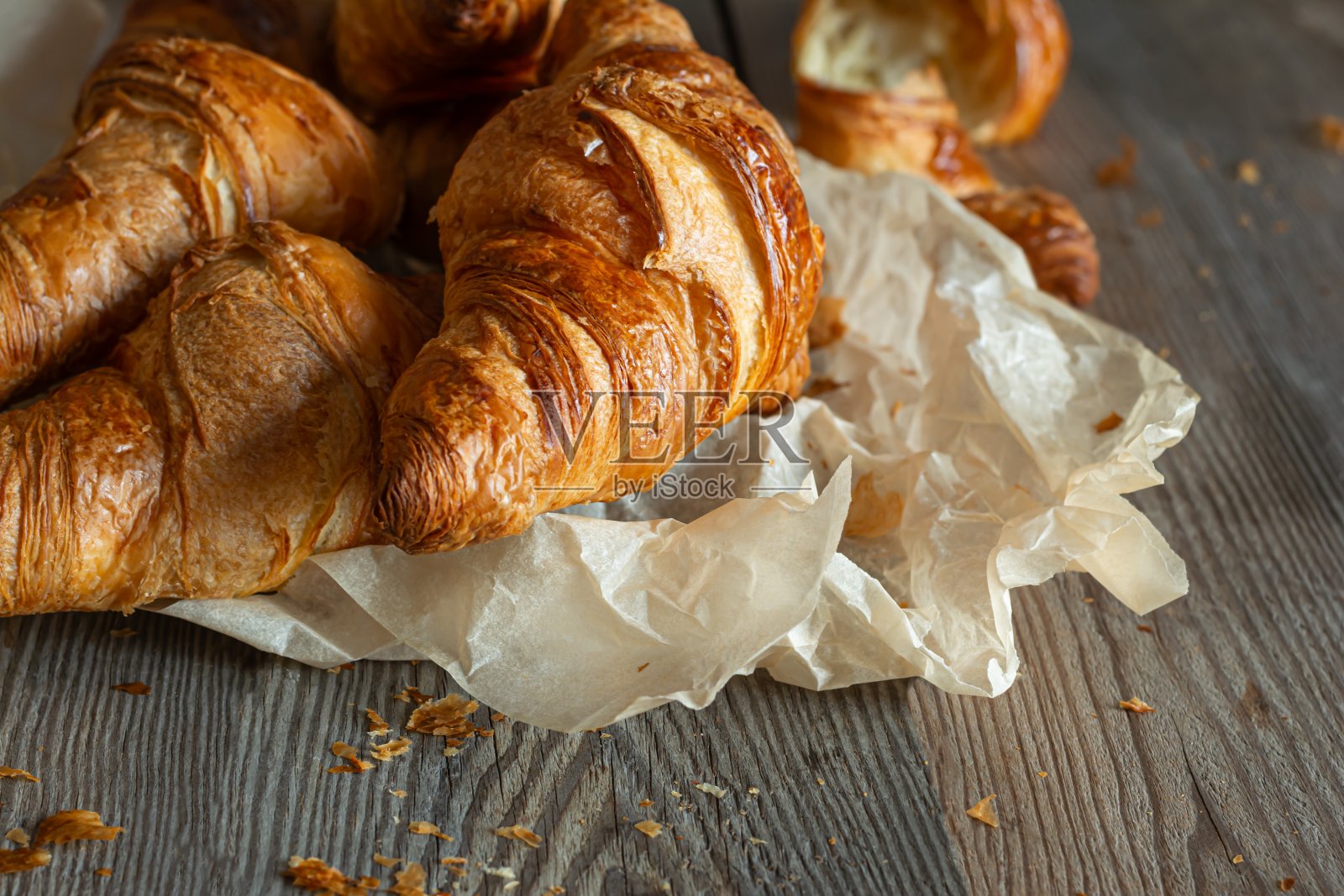 木质背景上新鲜酥脆的法式羊角面包。传统的红扑扑的糕点(包子)是早餐,美味的甜点。照片摄影图片