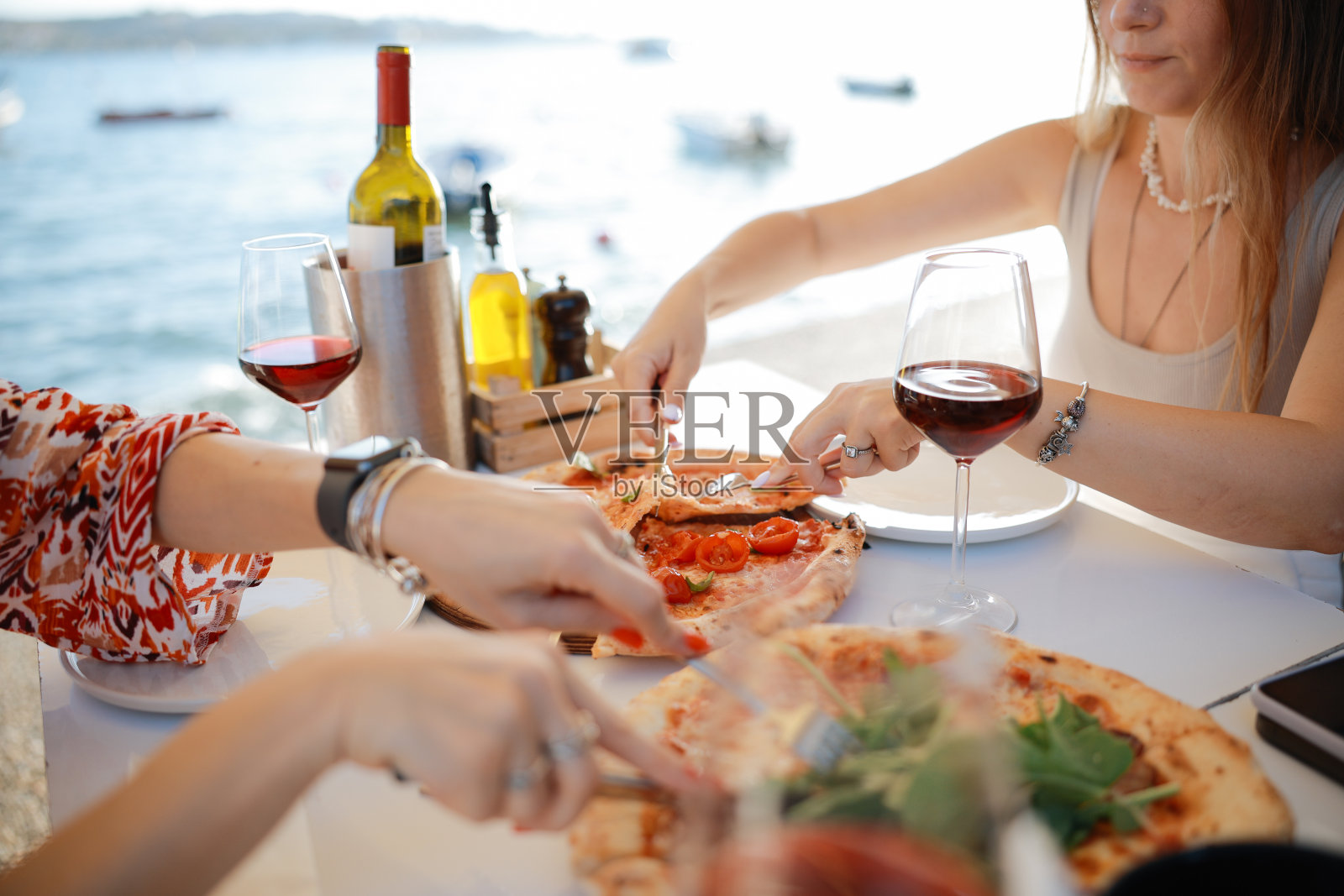 两位女性朋友在夏日街咖啡馆外面的露台上笑着喝酒的特写照片摄影图片