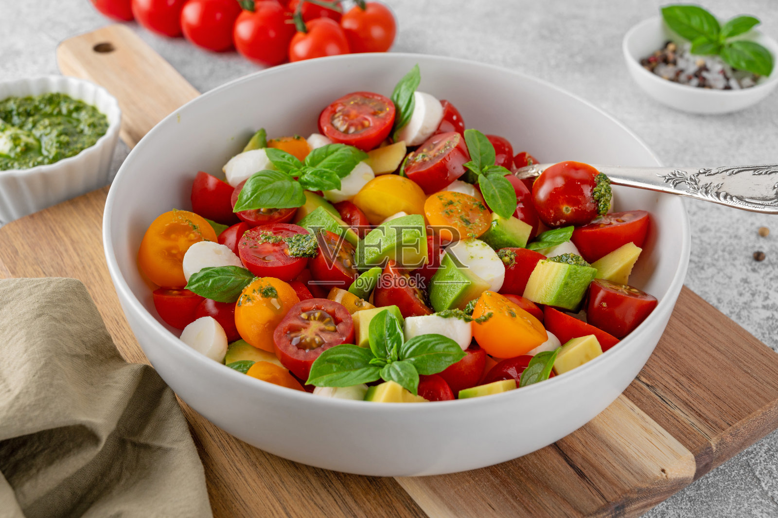 卡普里斯沙拉配圣女果,迷你马苏里拉奶酪球,鳄梨,香蒜酱和新鲜罗勒。健康素食餐。照片摄影图片