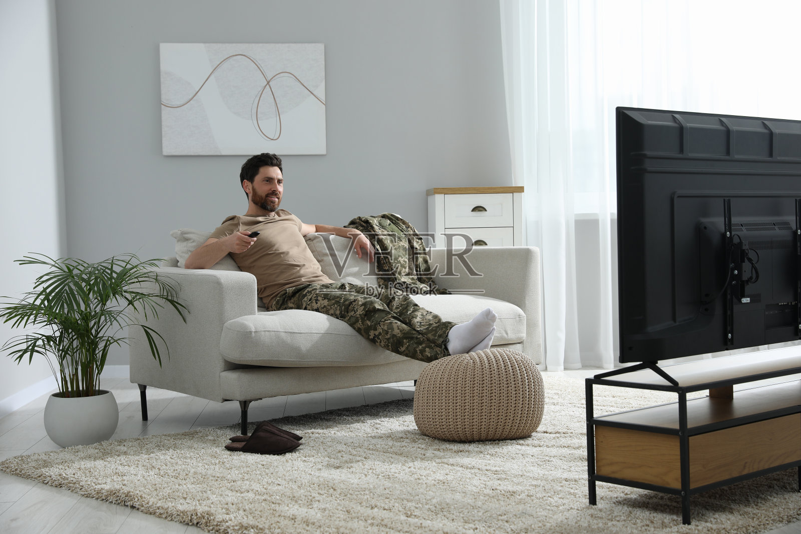 快乐的士兵在客厅的沙发上看电视。服兵役照片摄影图片