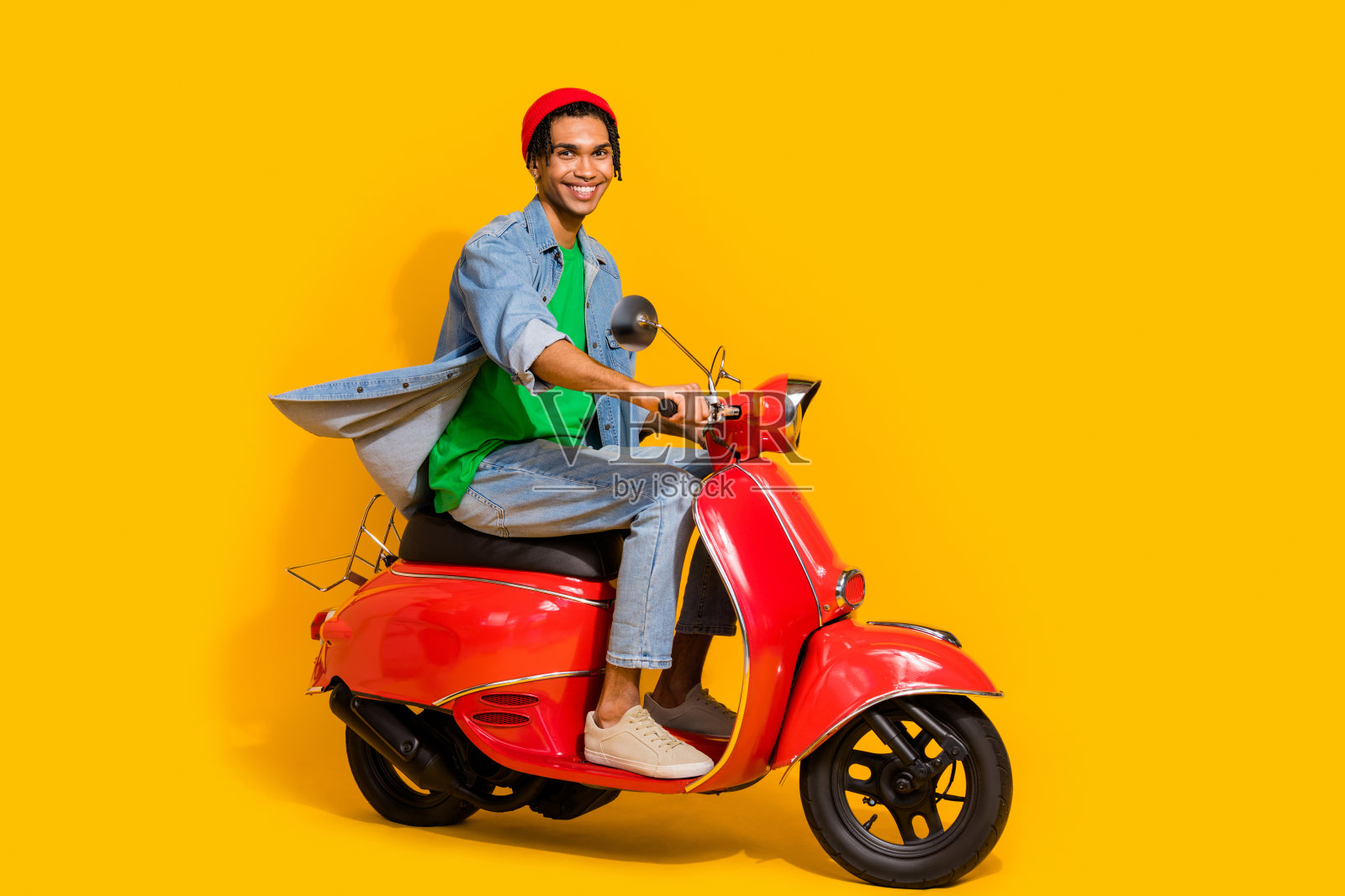 漂亮的年轻人的全尺寸照片,驾驶红色复古摩托车,穿着时髦的牛仔裤,黄色背景孤立照片摄影图片