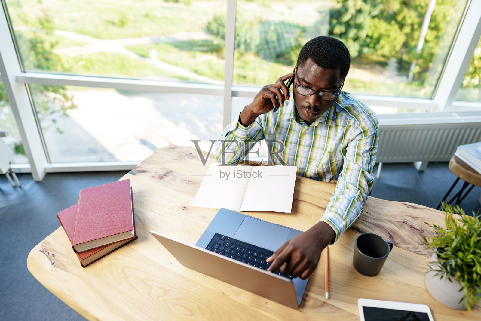 非洲男性企业家在办公室用手机和笔记本电脑工作照片摄影图片