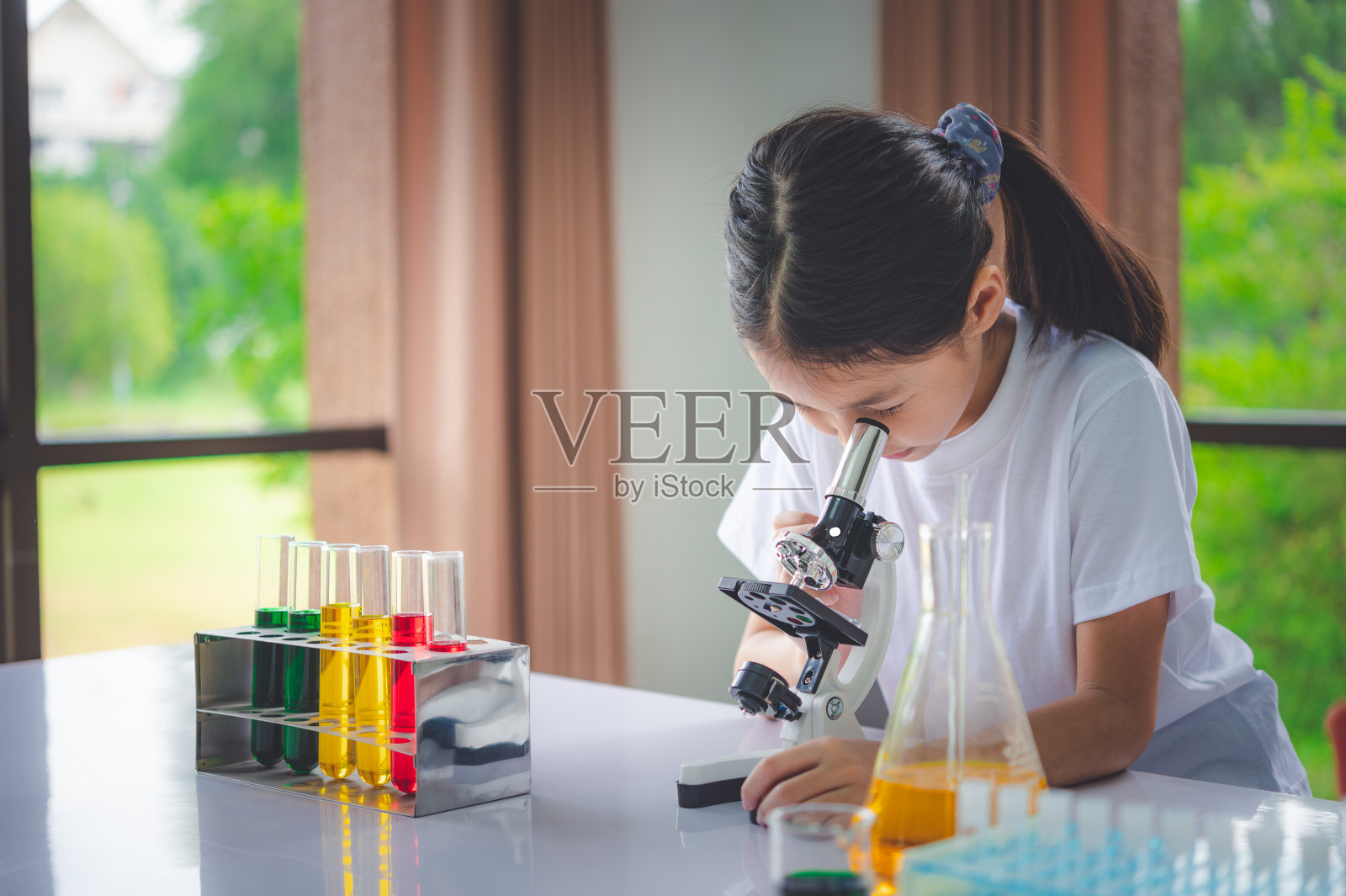 小科学家通过显微镜和装满化学物质的试管来学习科学和实验。照片摄影图片