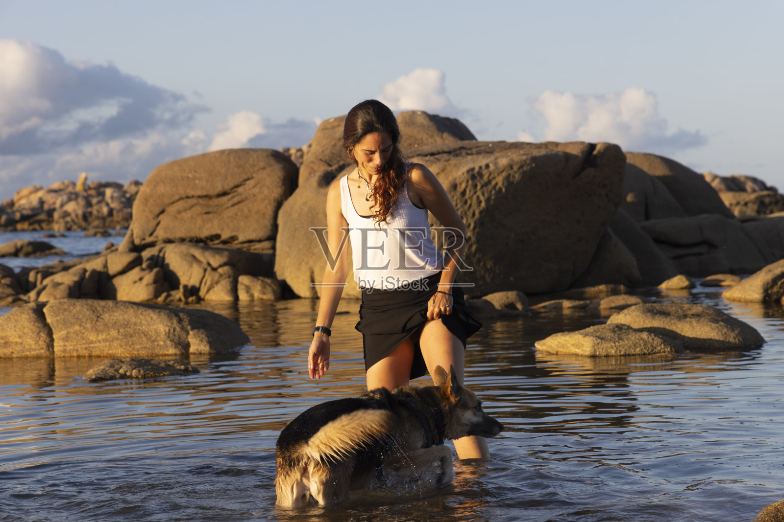 年轻的拉丁女人在沙滩上和狗玩耍照片摄影图片