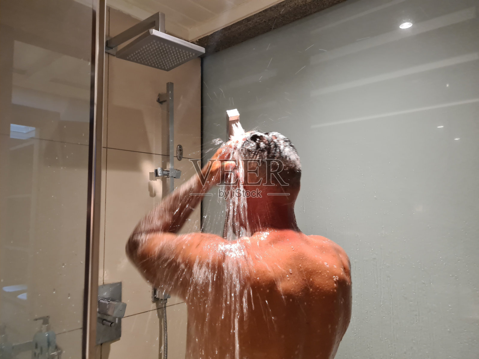 男子在豪华的浴缸里淋浴,在雨水中洗头照片摄影图片