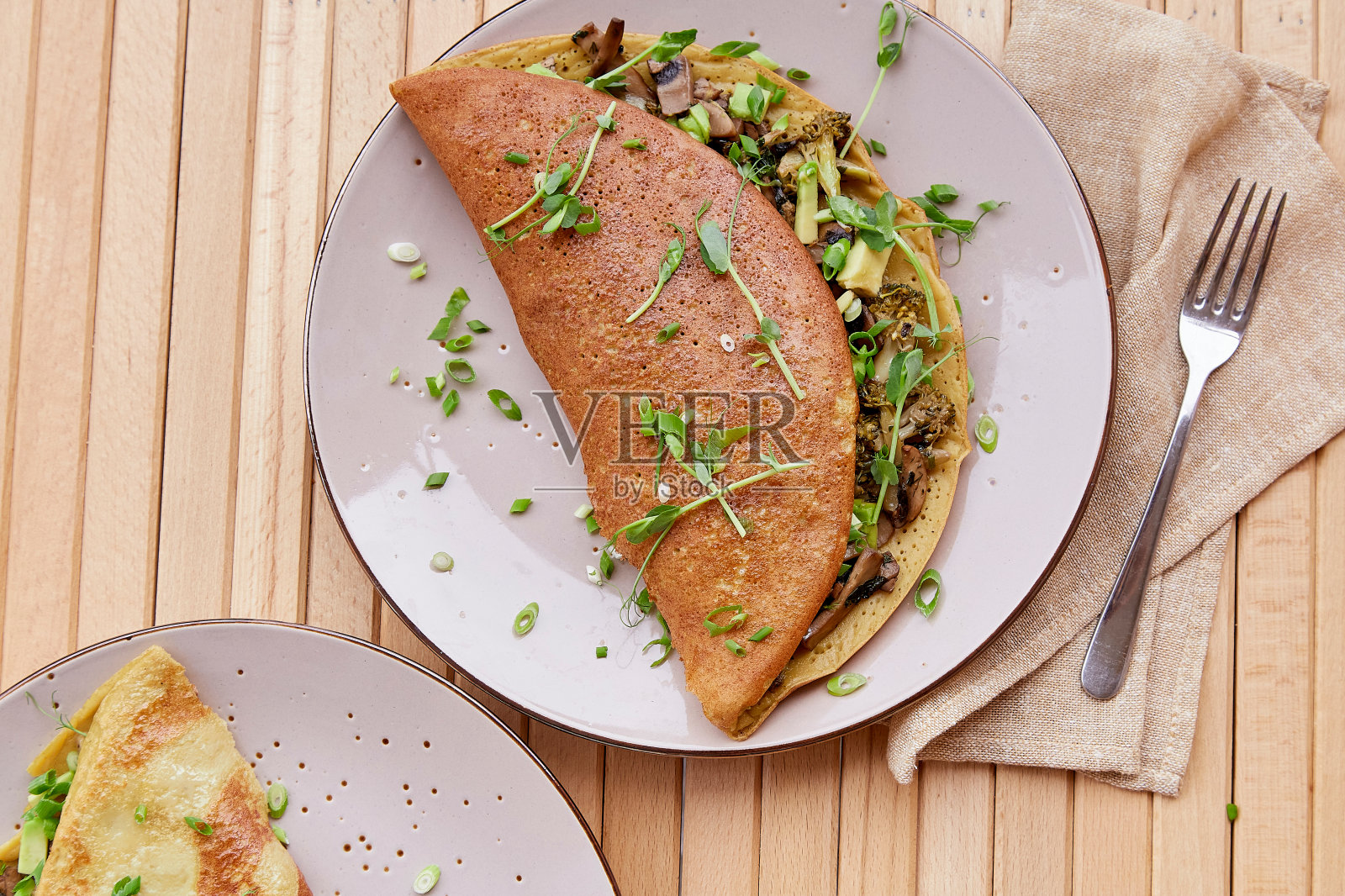 用蘑菇、豌豆芽和鳄梨做的素食煎饼。两个人的健康早餐放在木桌上。照片摄影图片