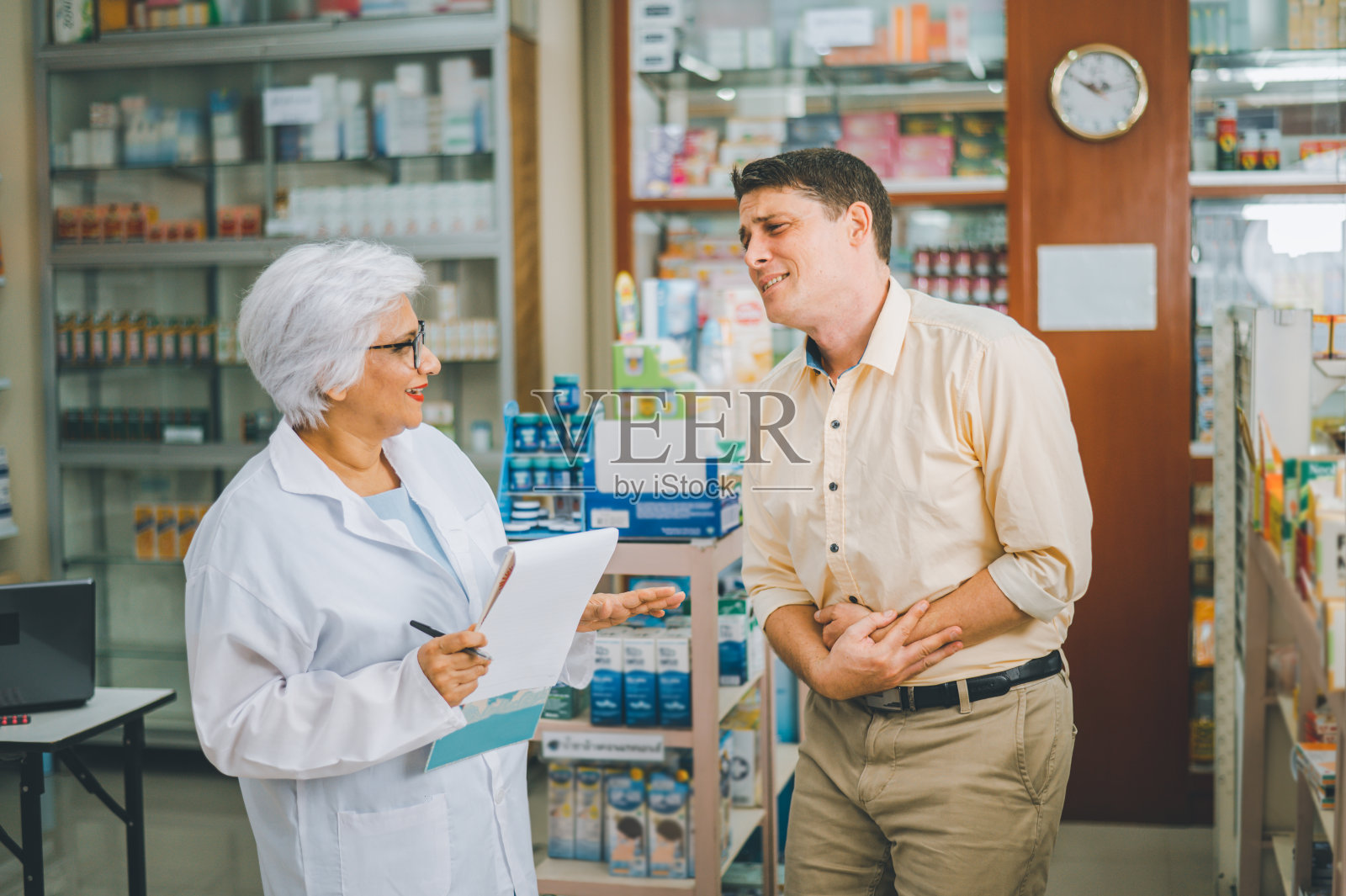 在现代药房,药剂师正在询问病人的病情,以便根据病人的症状开药。照片摄影图片