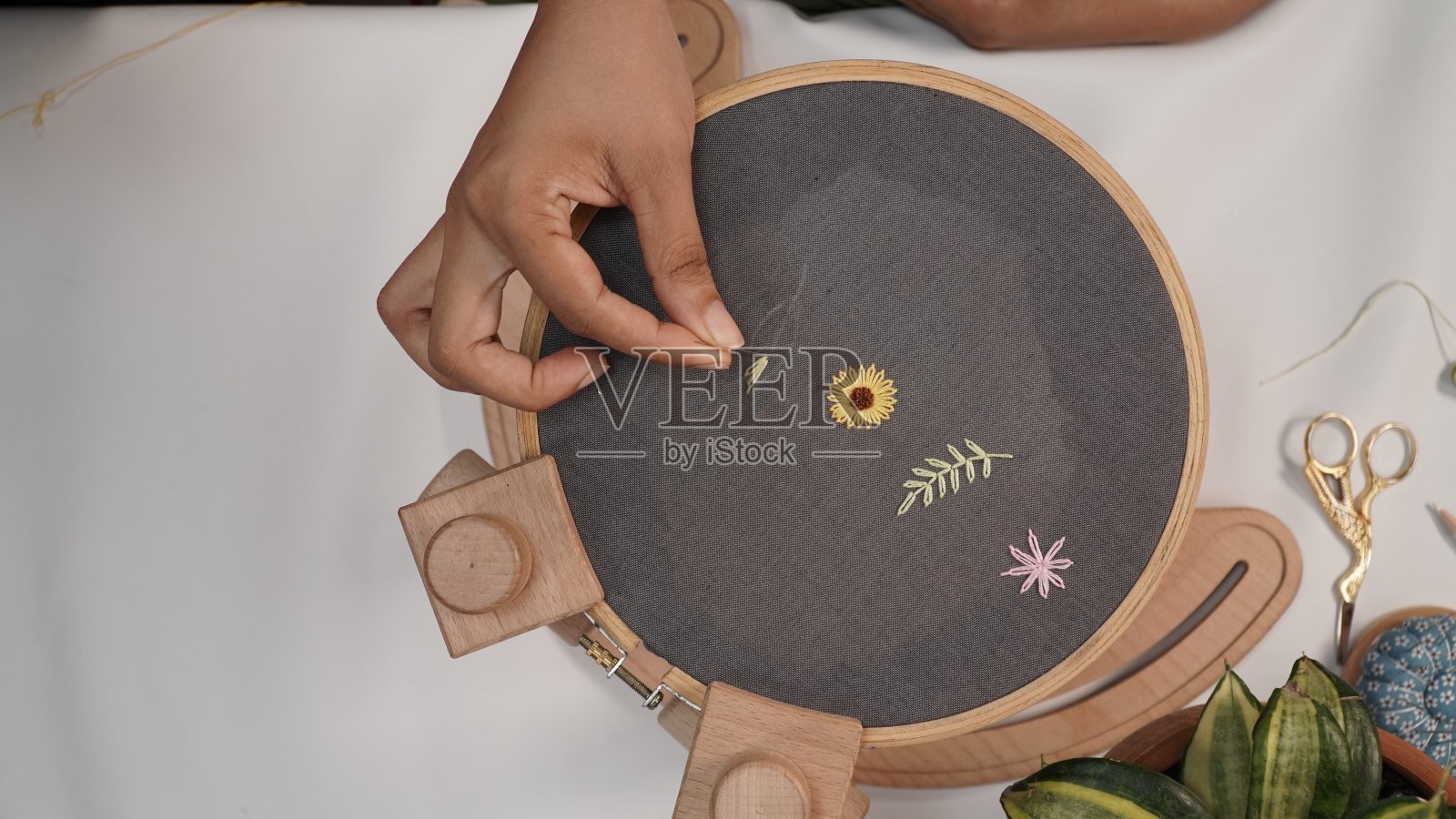 手工刺绣的木箍与花。手工缝制棉质灰色织物。照片摄影图片