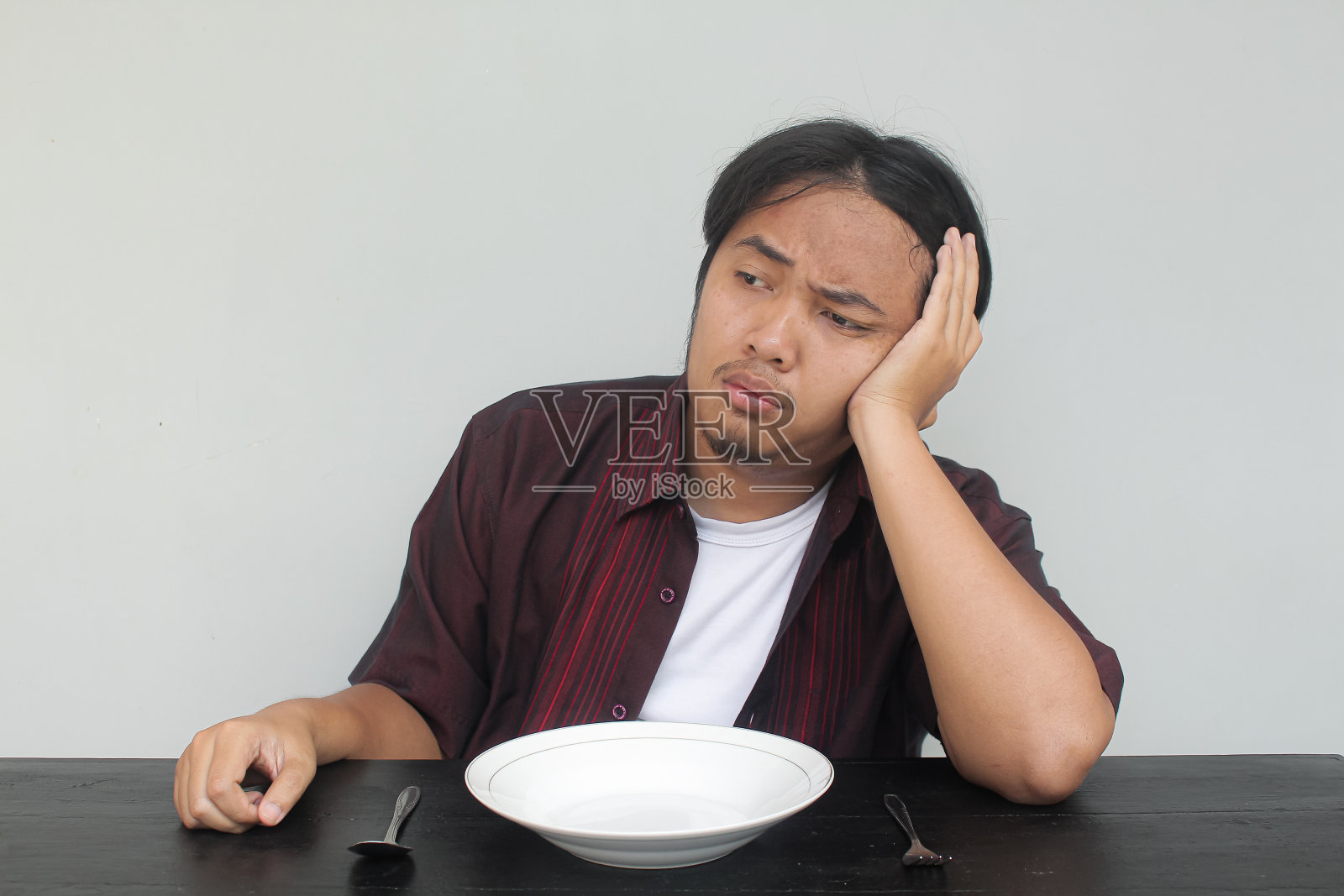 年轻的亚洲人坐在空盘子前照片摄影图片