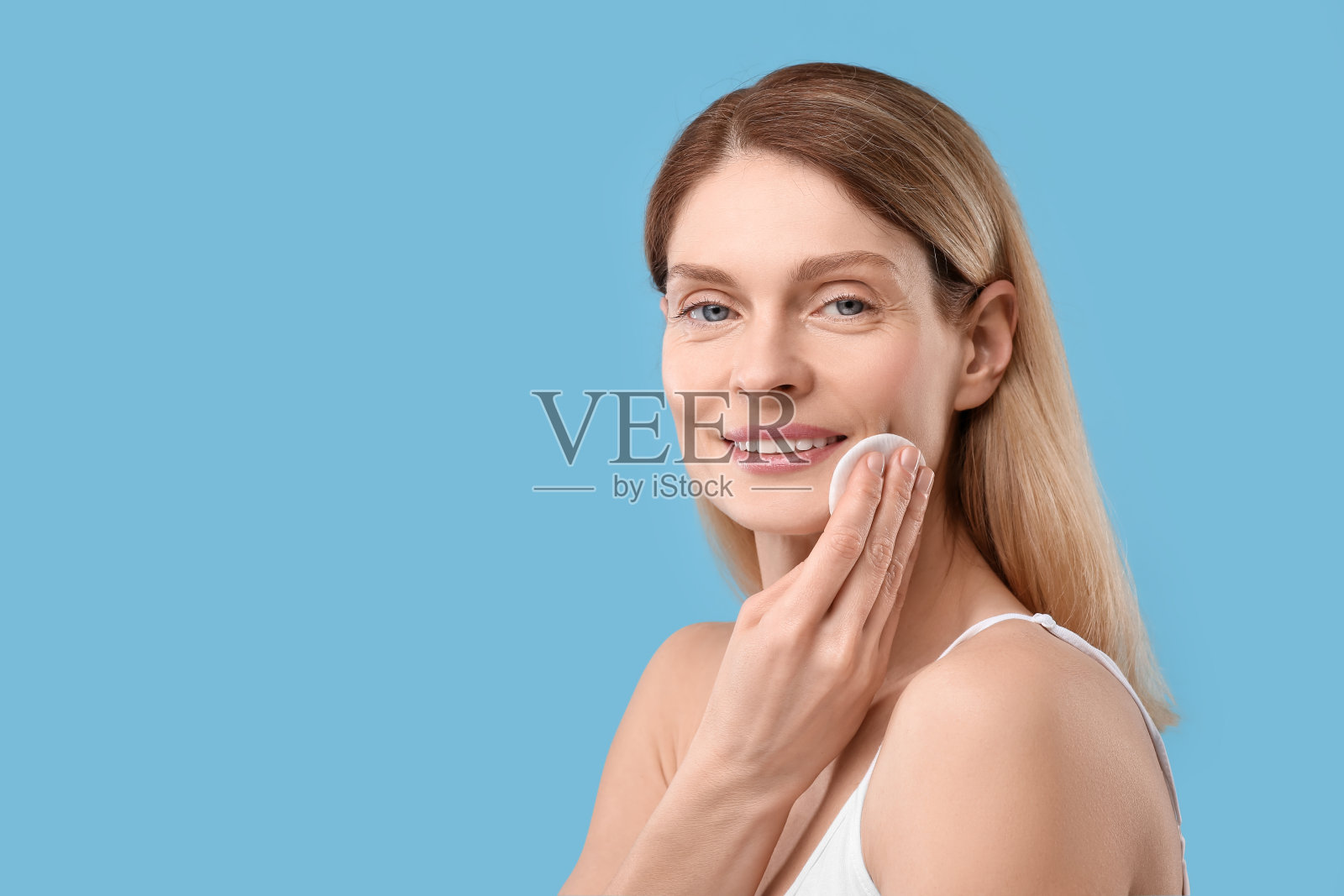 美女卸妆用化妆棉在浅蓝色的背景,文字的空间照片摄影图片