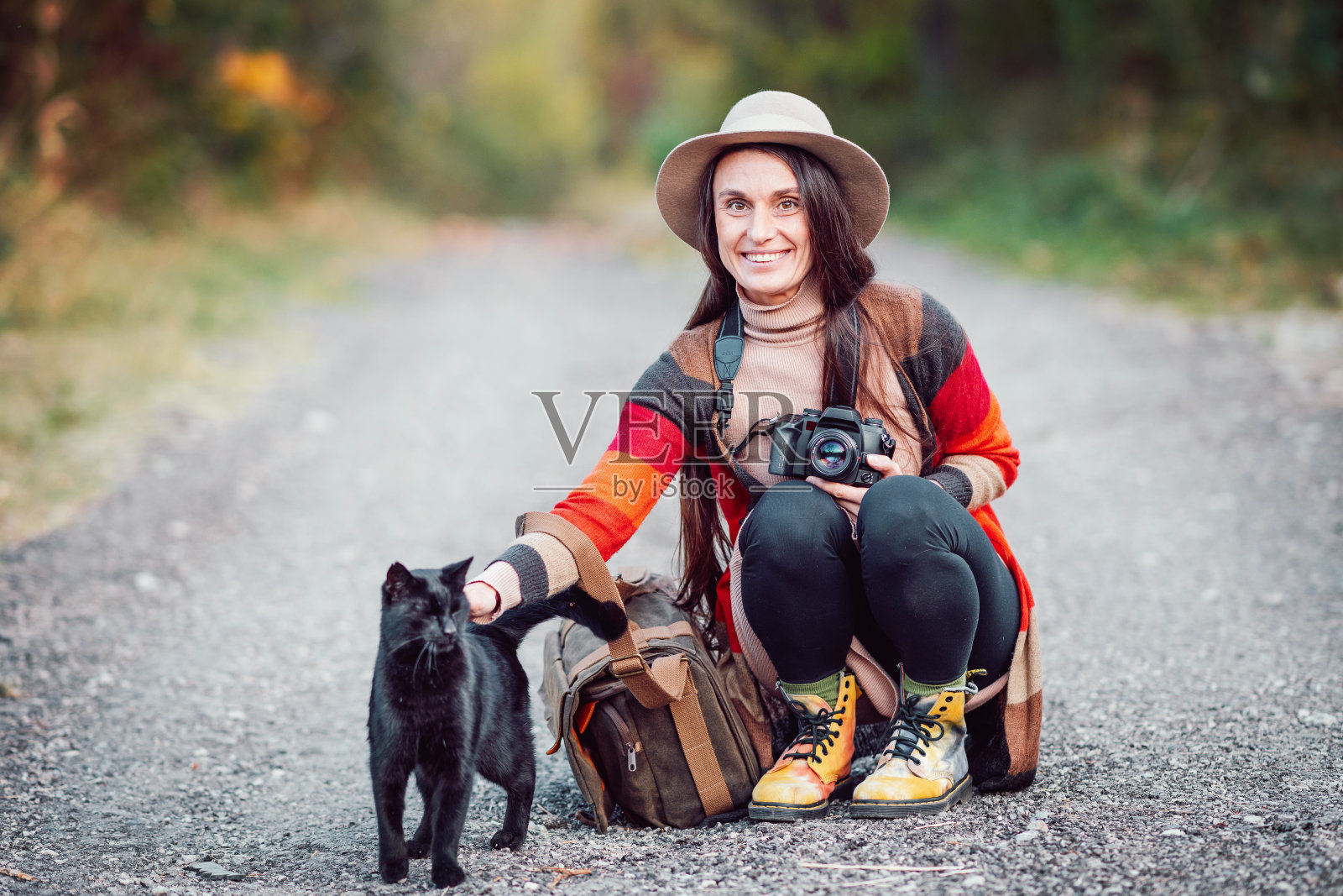 女摄影师和一只黑猫在秋天的森林里照片摄影图片