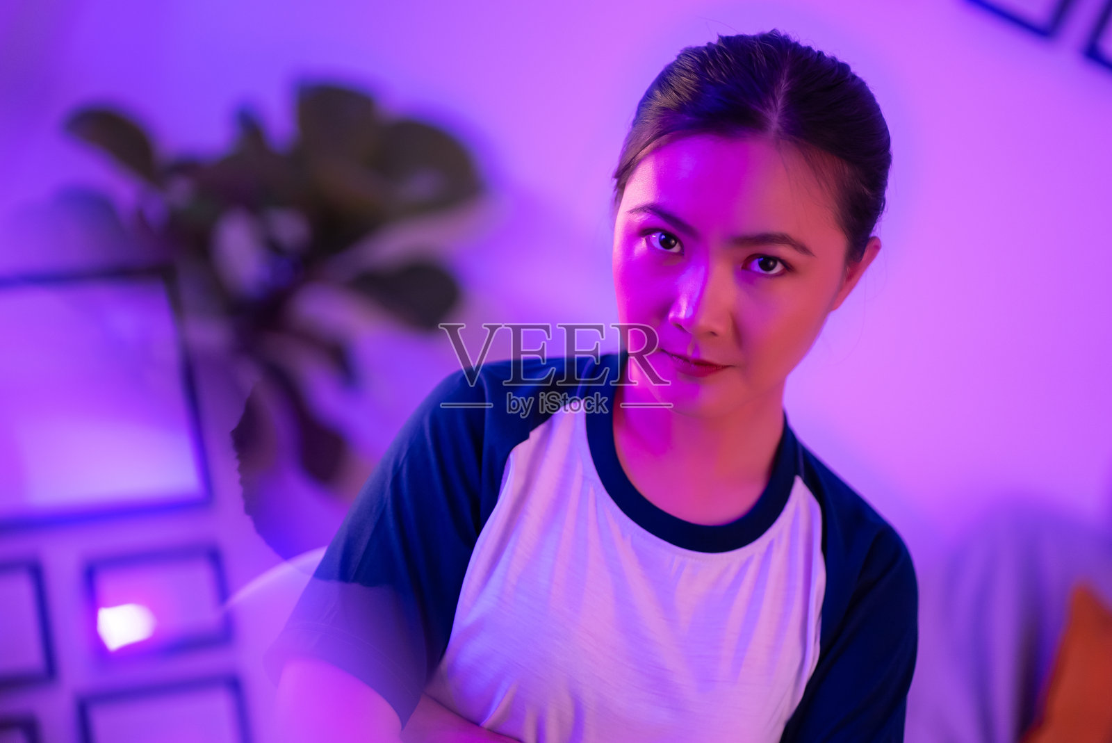 一个自信的亚洲女人坐在客厅的霓虹灯的肖像。照片摄影图片