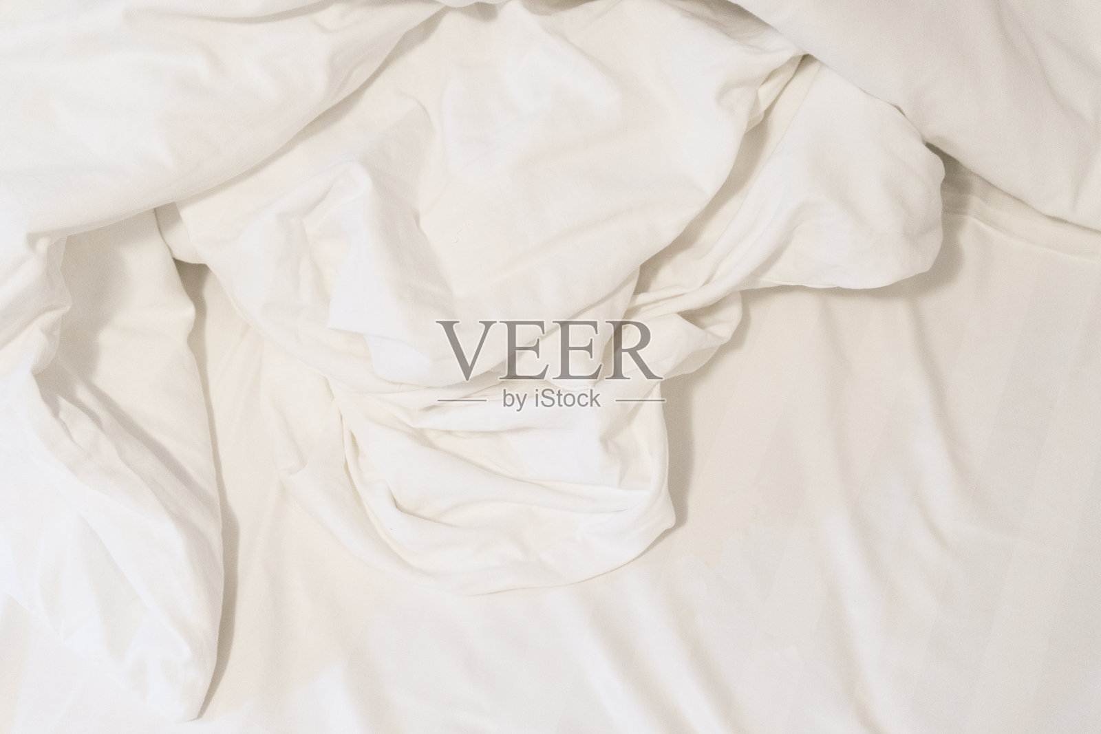 早上醒来后。旅馆里床上的皱巴巴的毯子,阳光洒在毯子上照片摄影图片