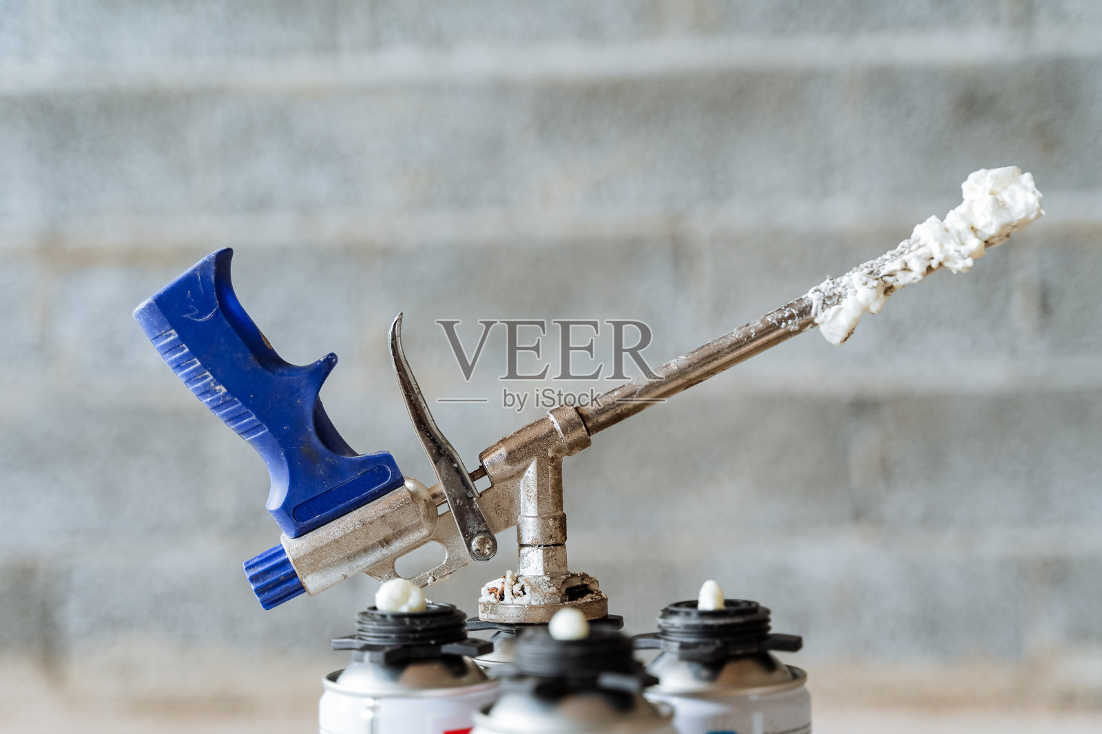 施工人员工作后弄脏工具,喷泡沫粘在金属管上的枪、工业工具上。照片摄影图片