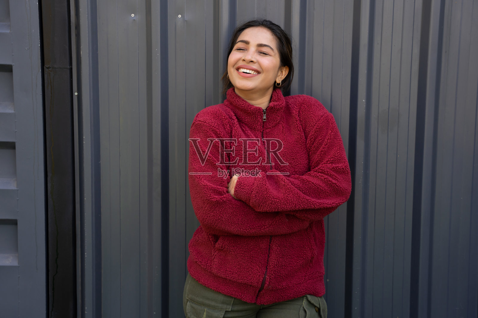 微笑着的年轻印度女子穿着温暖的红色冬季夹克,孤立地站在黑色的背景上照片摄影图片