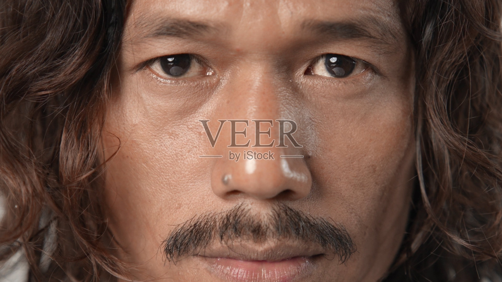 悲伤的亚洲男人凝视。长长的卷发。亚洲人留着胡子越南人。照片摄影图片