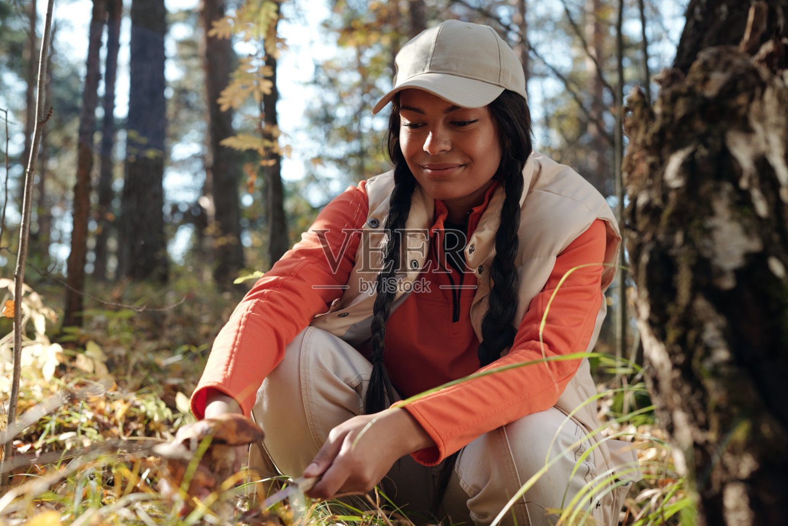 戴着帽子的非裔美国女孩在把牛肝菌放进篮子之前正在切牛肝菌照片摄影图片