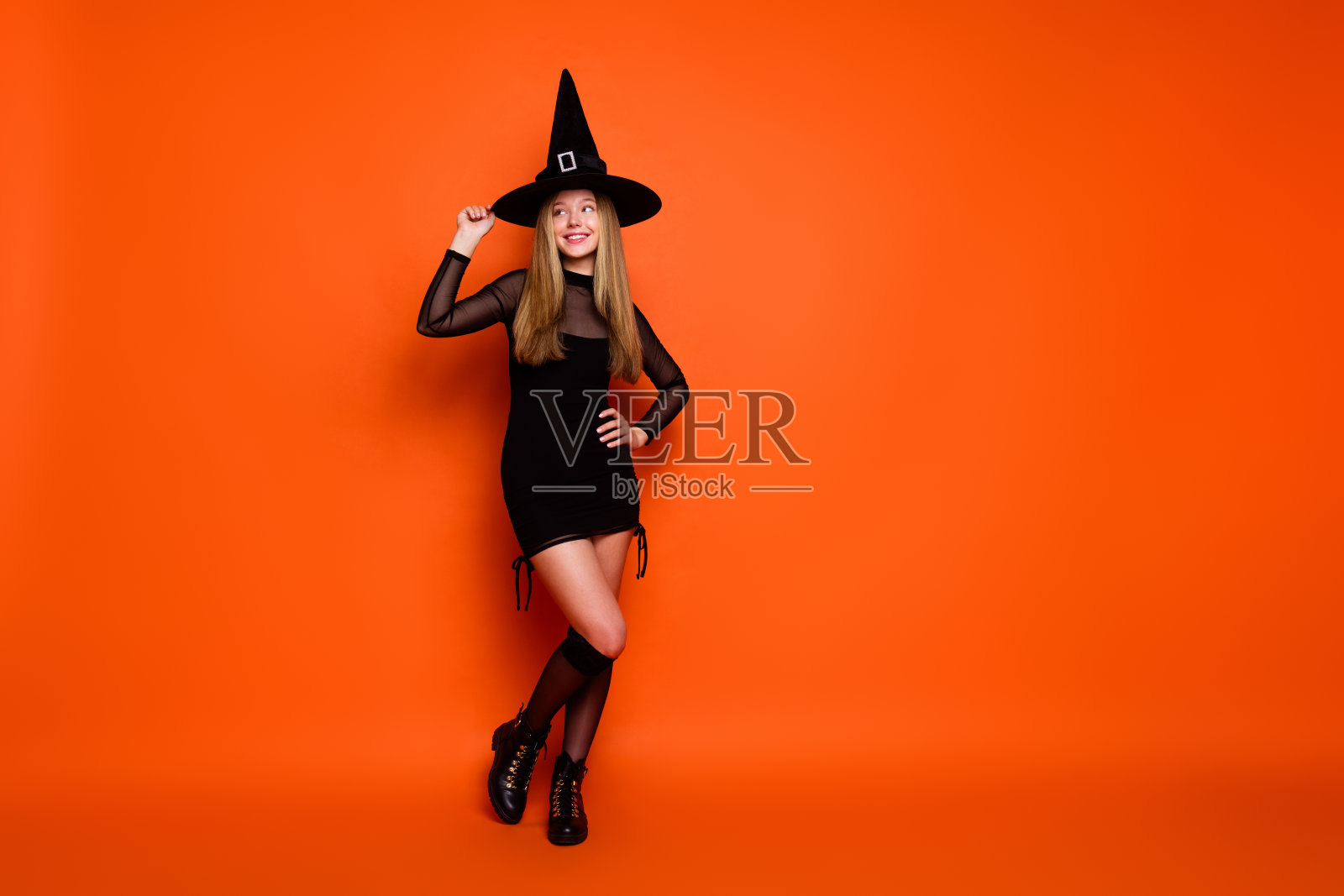 完整的肖像迷人的魔术师女孩触摸锥帽看起来空的空间和孤立的橙色背景照片摄影图片