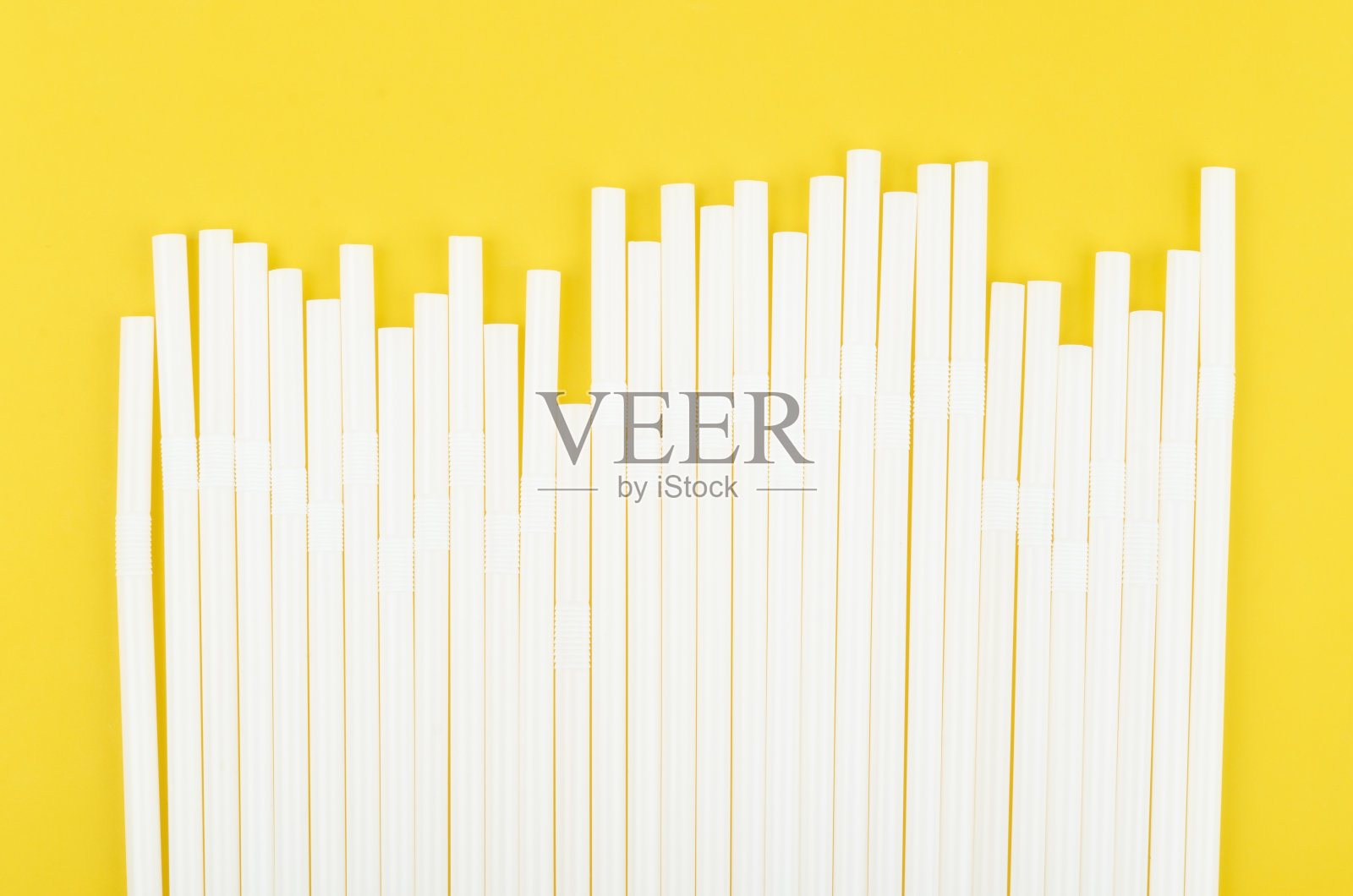 黄色背景上的白色吸管。照片摄影图片