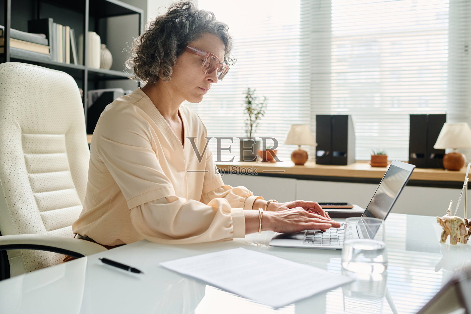 严肃的成熟女性企业家在工作场所的笔记本电脑键盘上打字照片摄影图片