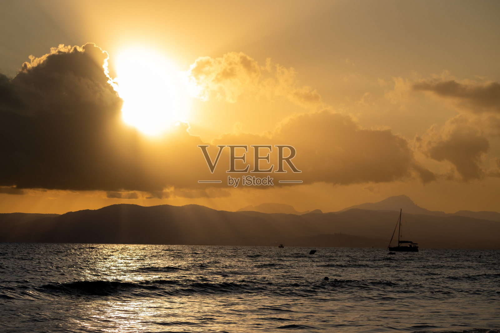 马略卡海滩上,云后的超级日落照片摄影图片