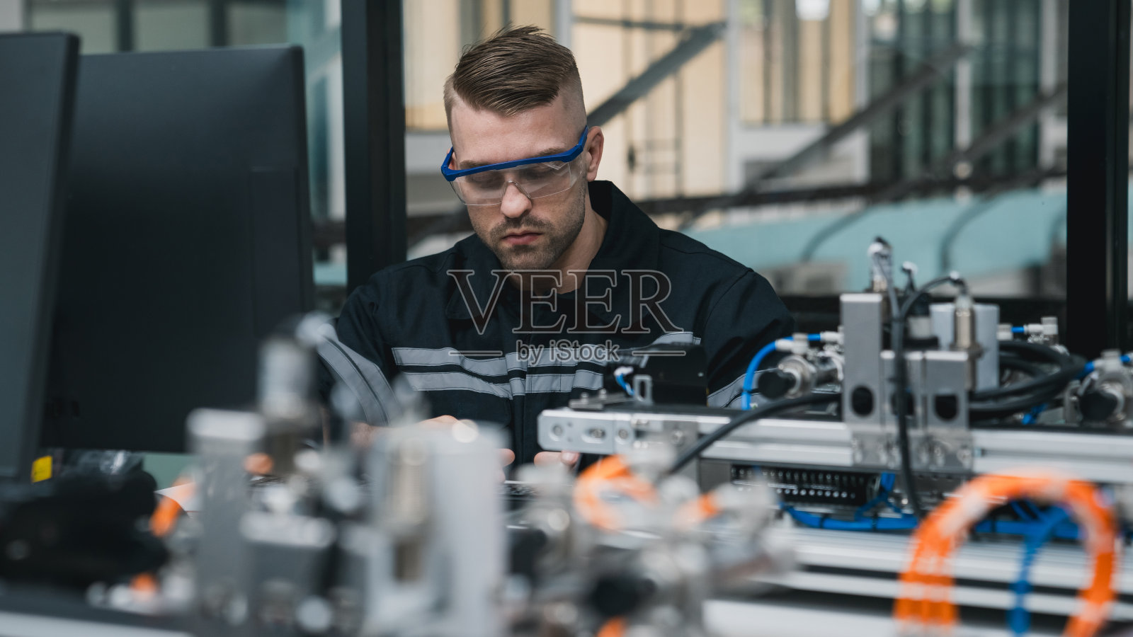 实习工程师在技术工作坊用电脑组装机械臂。服务工程师手持机器人控制器并检查机械臂焊接硬件。照片摄影图片