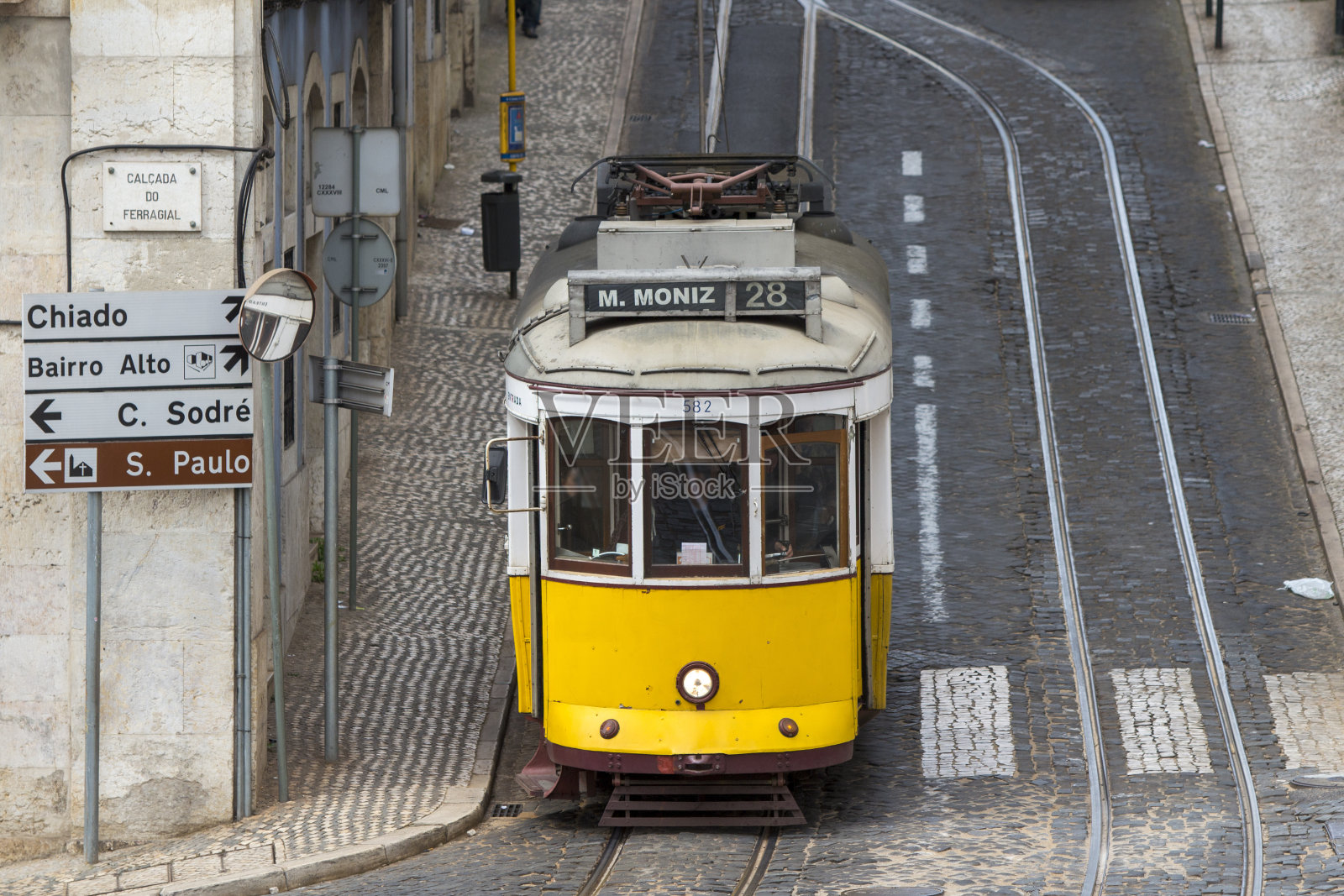 葡萄牙里斯本街道上的28号有轨电车在轨道和传统石头上行驶。照片摄影图片