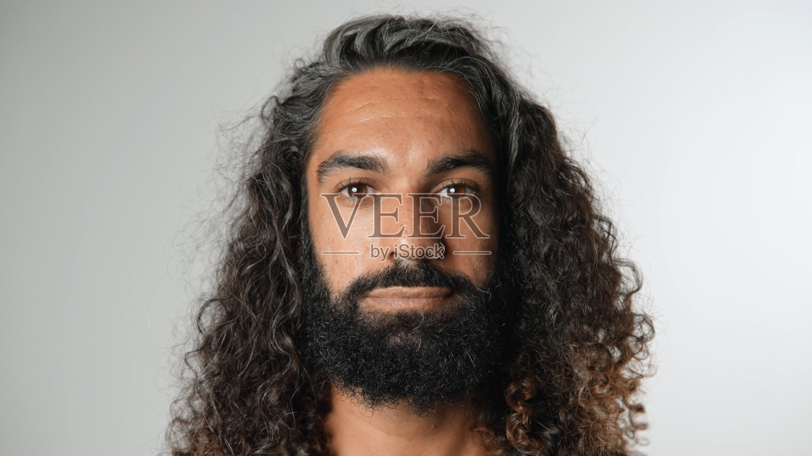 拉丁裔男子面部肖像,长波浪卷发。有胡子的家伙。严肃的人。照片摄影图片