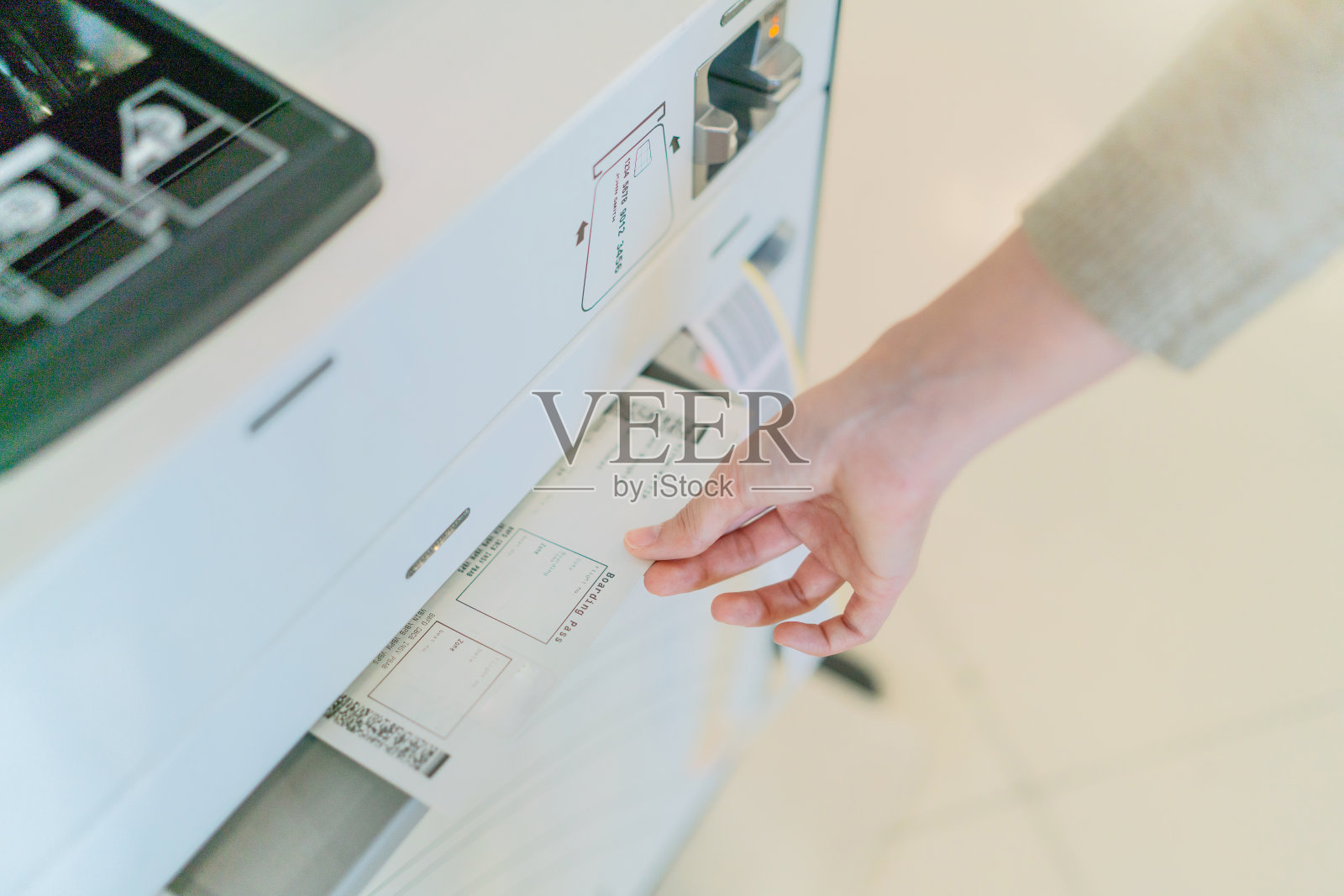 打印的自助值机登机牌特写。一名年轻的亚洲女子在机场自助自助值机亭办理登机手续。准备好旅行了。照片摄影图片