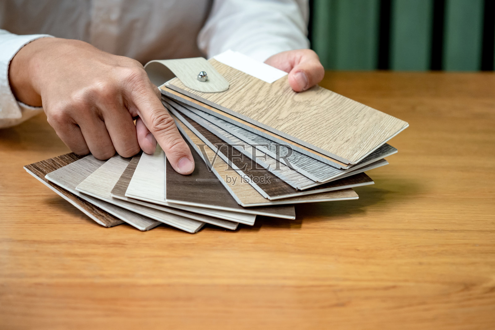 设计师在室内建筑和家具设计工作中手工选择和指向木质纹理层压板材料样品或木质调色板目录指南。照片摄影图片