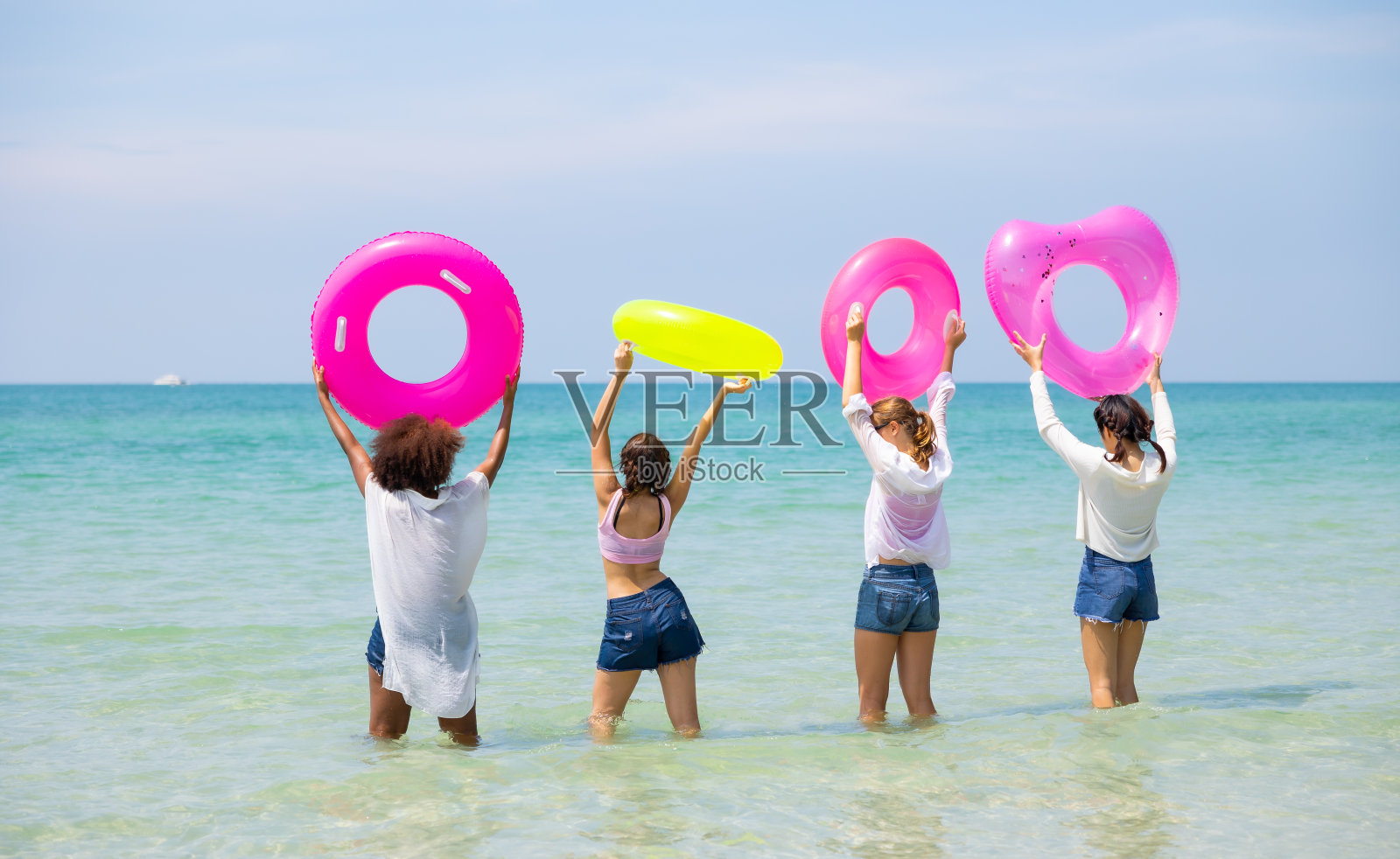 自由浮动。一群不同的少女在海滩上。四个十几岁的女孩在热带海滩上玩充气环。暑假旅行。照片摄影图片