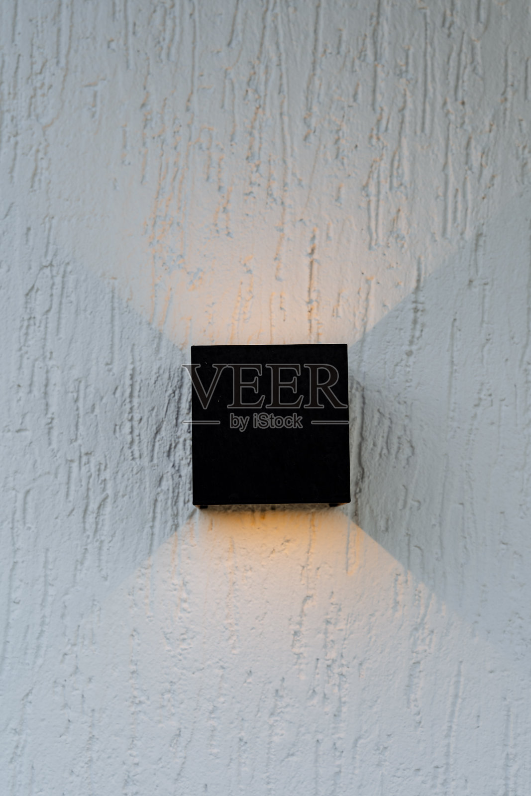 建筑立面的灯光是黄色的,房子墙上的黑色灯笼发出温暖的光谱,这是一盏卤素灯。现场照明。照片摄影图片