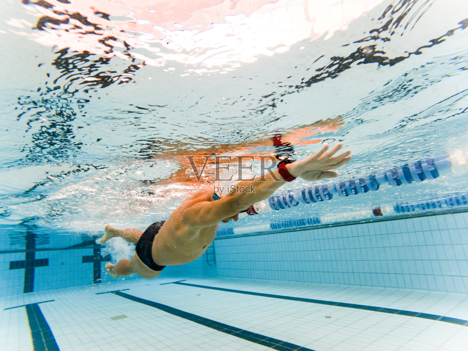 一个被截肢的成年男子穿着运动服在游泳池里游泳。残疾游泳运动员,截肢运动员。动机和决心。照片摄影图片