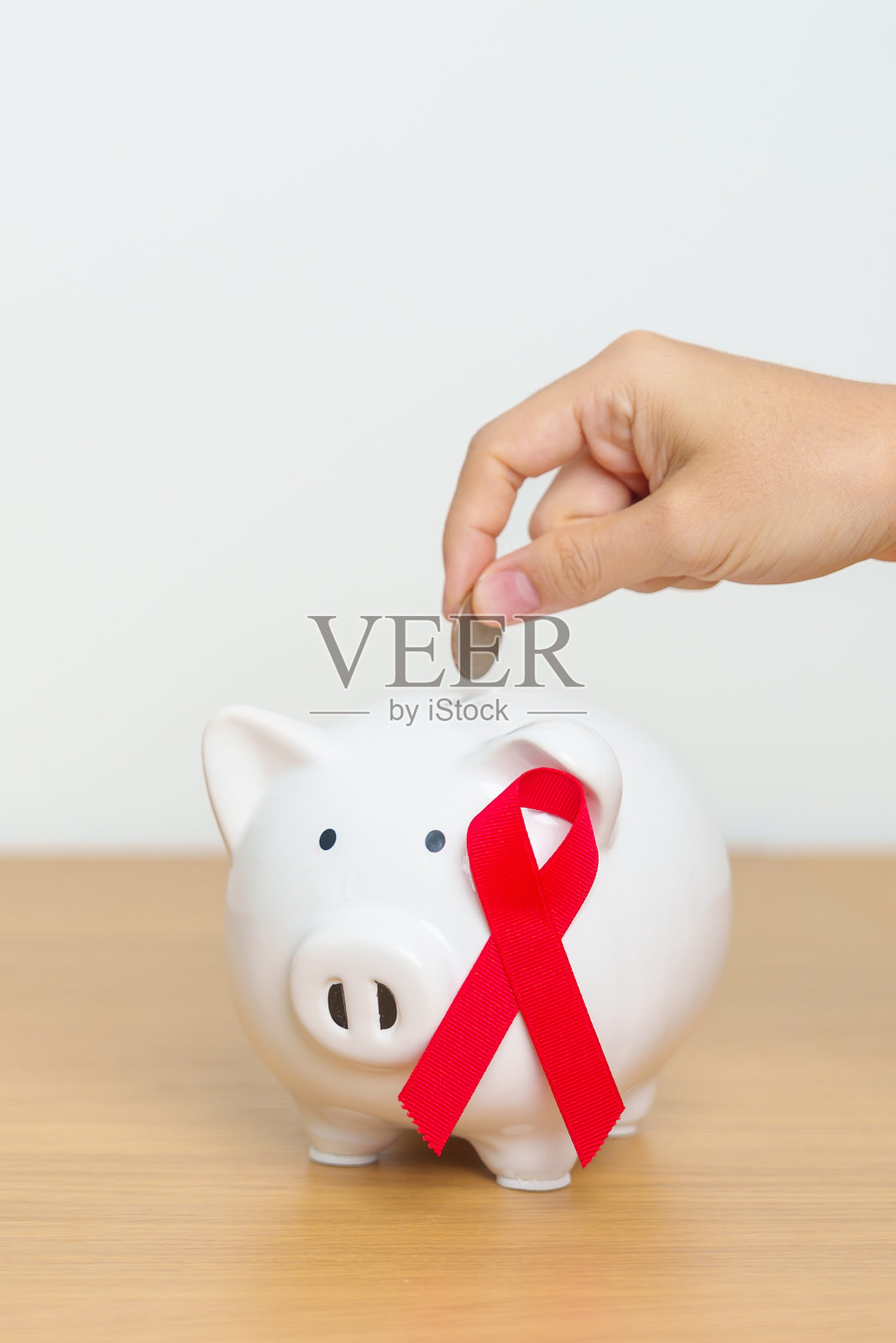 12月世界艾滋病日,获得性免疫缺陷综合征,红丝带与存钱罐一起支持疾病生命。健康、捐赠、慈善、运动、省钱、基金和世界癌症日的概念照片摄影图片
