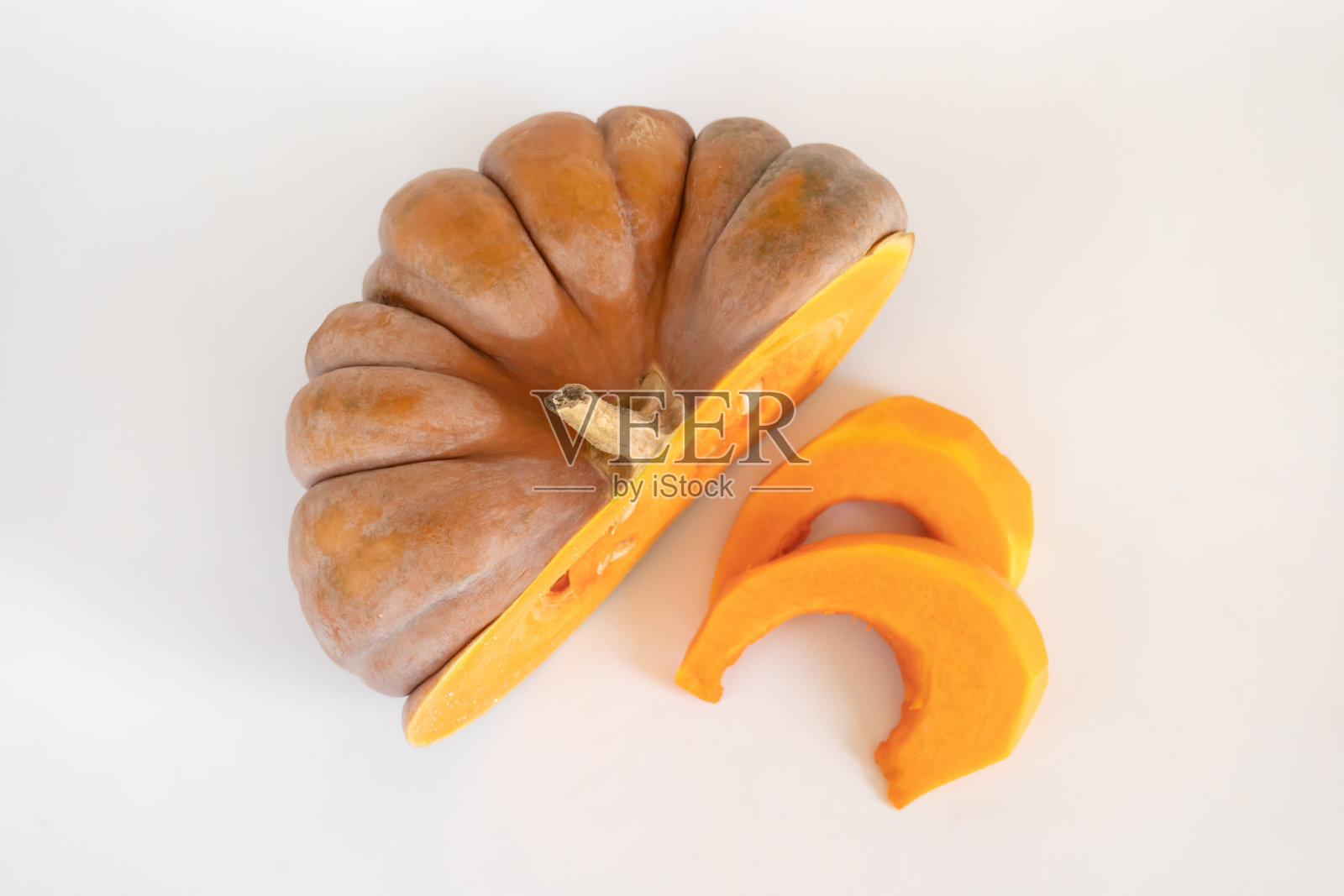 半个南瓜和南瓜果肉,在白底上切成块。照片摄影图片