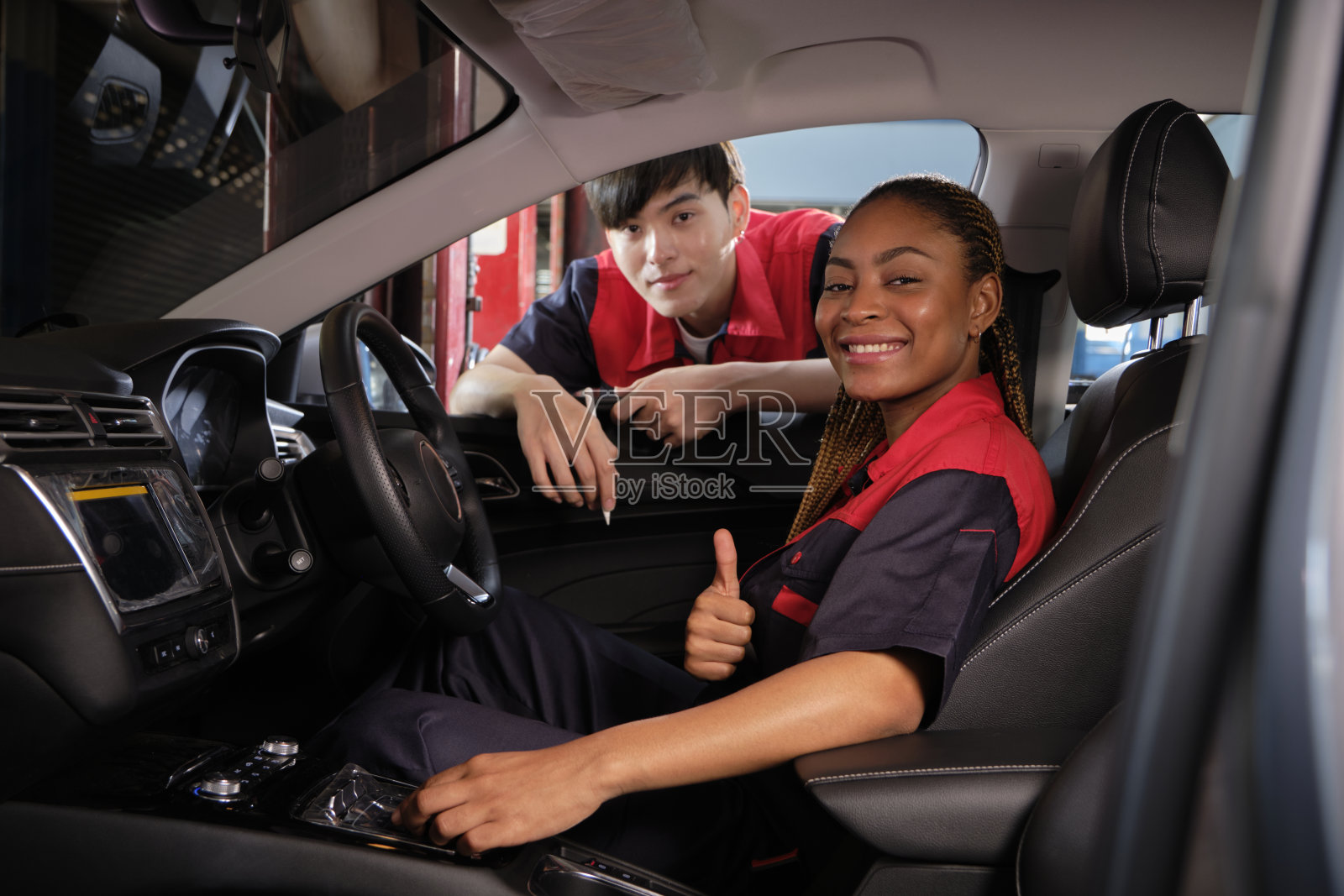 两个汽车工人在汽车内部检查维修清单。照片摄影图片