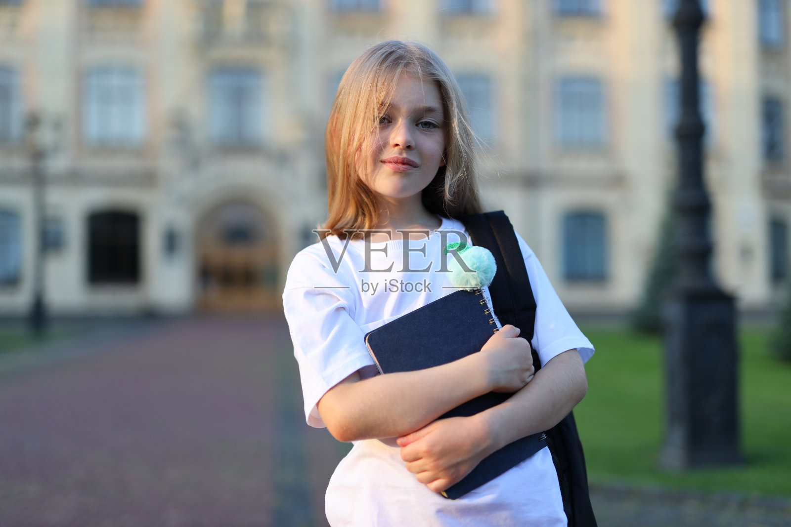 在一个阳光明媚的夏日,年轻的女学生站在城市的户外,在大学校园里学习,散发着美丽和自信。照片摄影图片