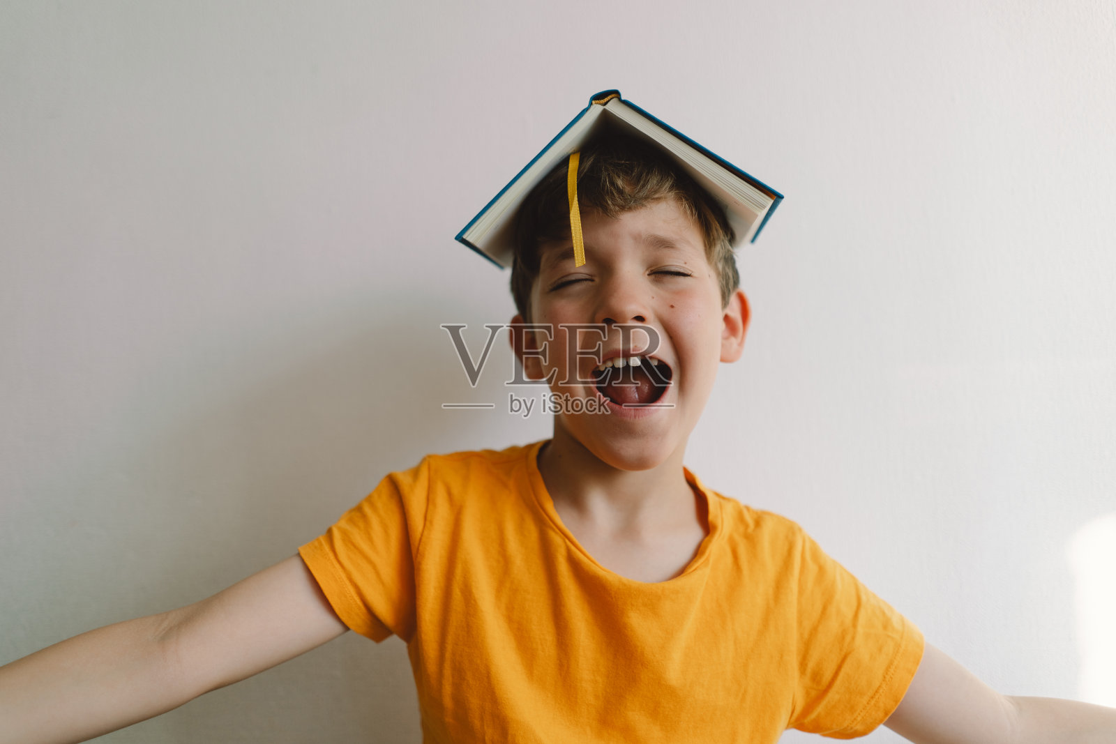 一个可爱的男孩正坐在柔软的软垫上看书。照片摄影图片