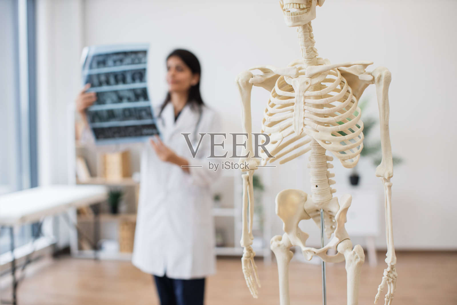 护士带着x光片站在现代人的骨骼旁照片摄影图片