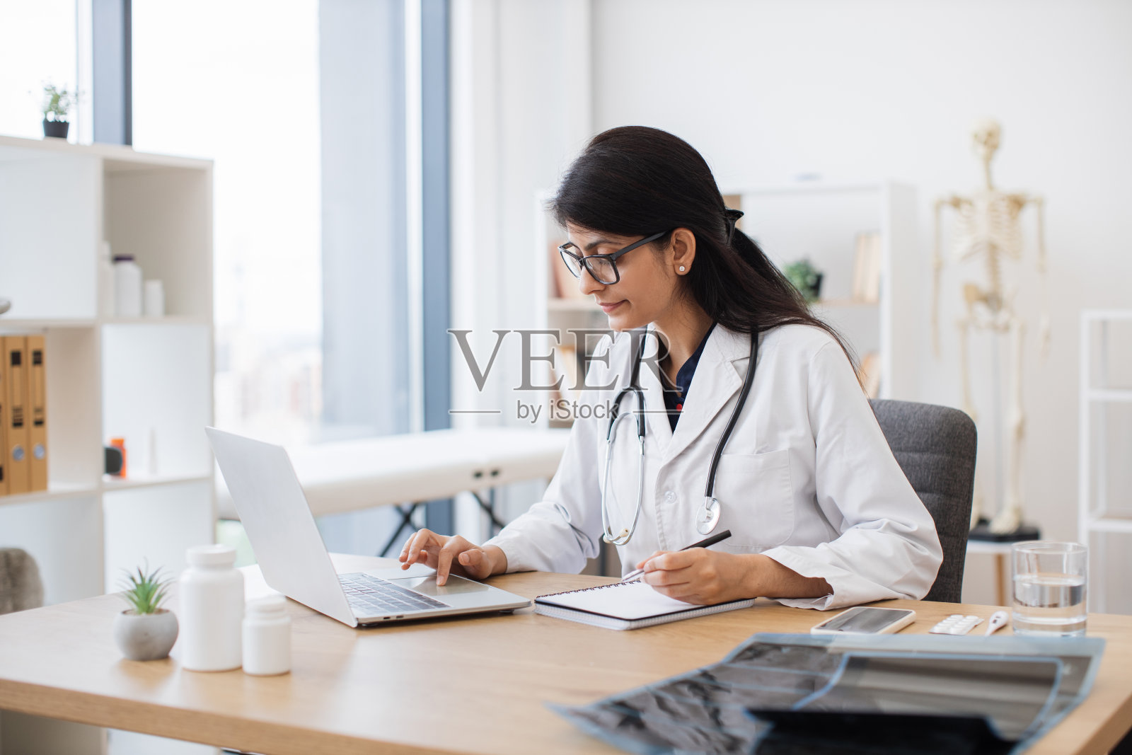 医生坐在健康中心的办公桌前使用电脑照片摄影图片