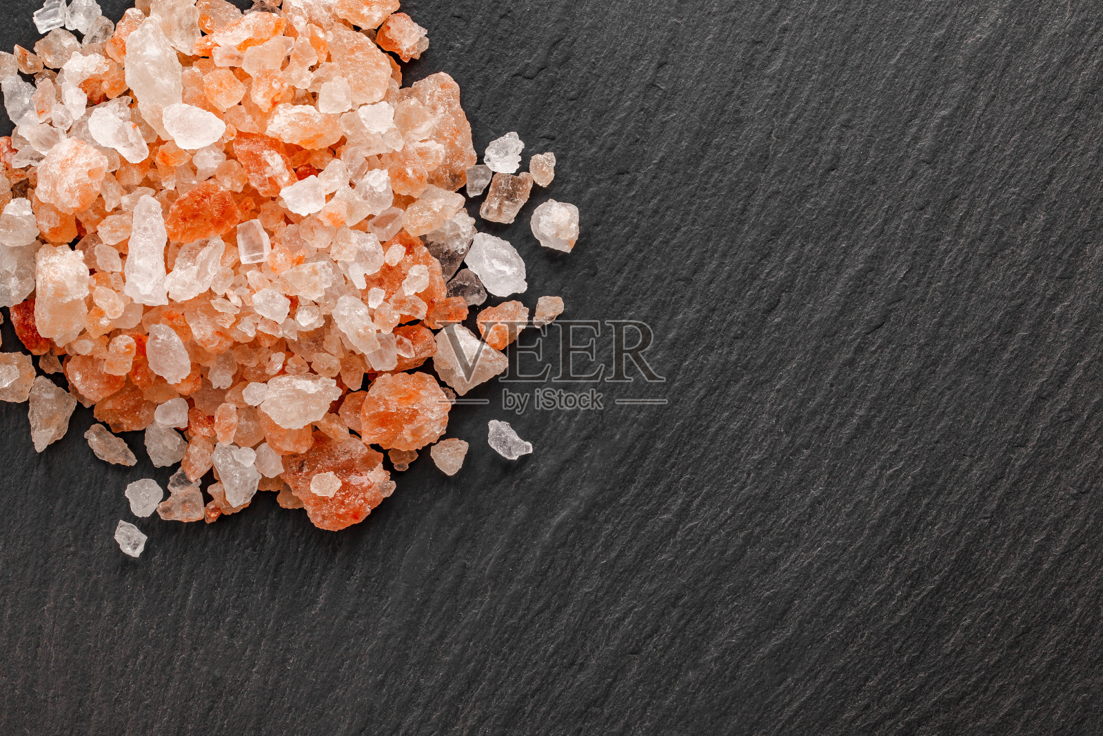 粉红色的盐,晶体特写,在深色板岩板上的顶视图照片摄影图片