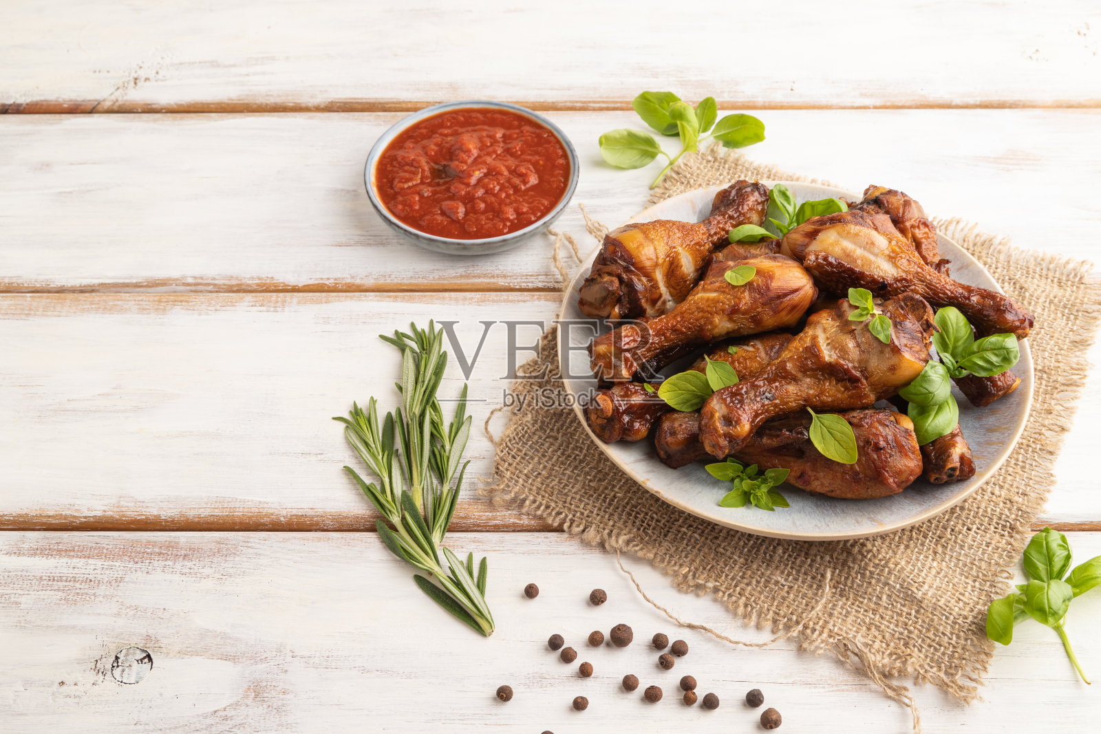 烟熏鸡腿放在白色木制背景的陶瓷盘子上。侧视图,复制空间。照片摄影图片